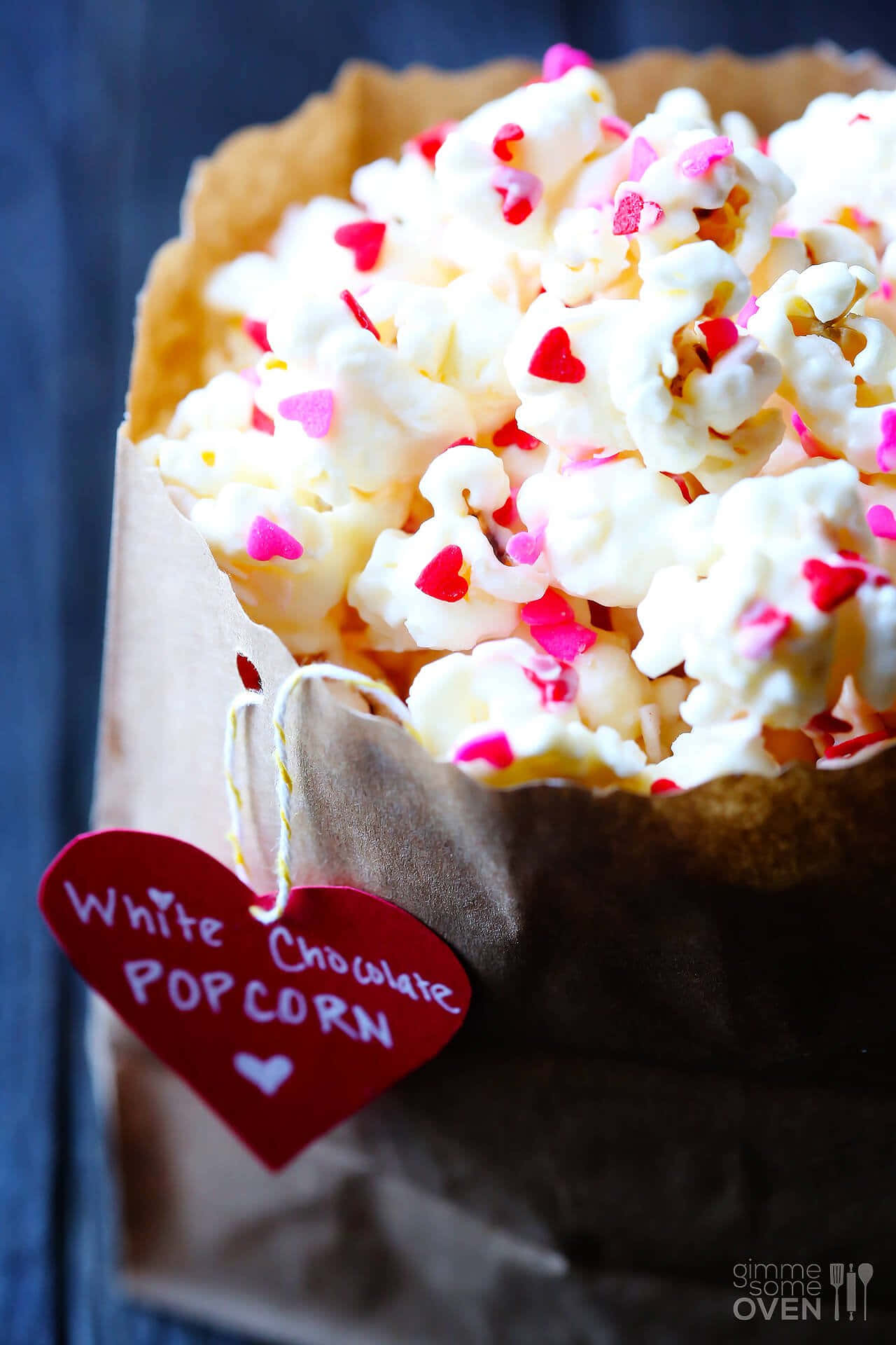 Popcorn 桌布 壁紙 — 一個棕色紙袋裝滿了白巧克力爆米花，上面撒滿粉紅色和紅色的心形糖粒。