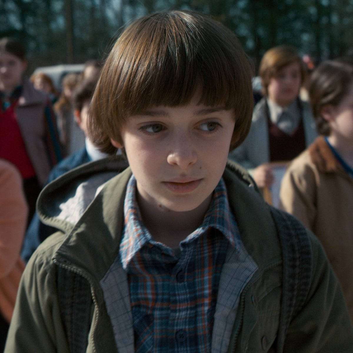 Netflix 桌布 壁紙 — 一個棕色頭髮、穿著格子襯衫的小男孩，在樹林戶外環境中，若有所思地望向鏡頭外。