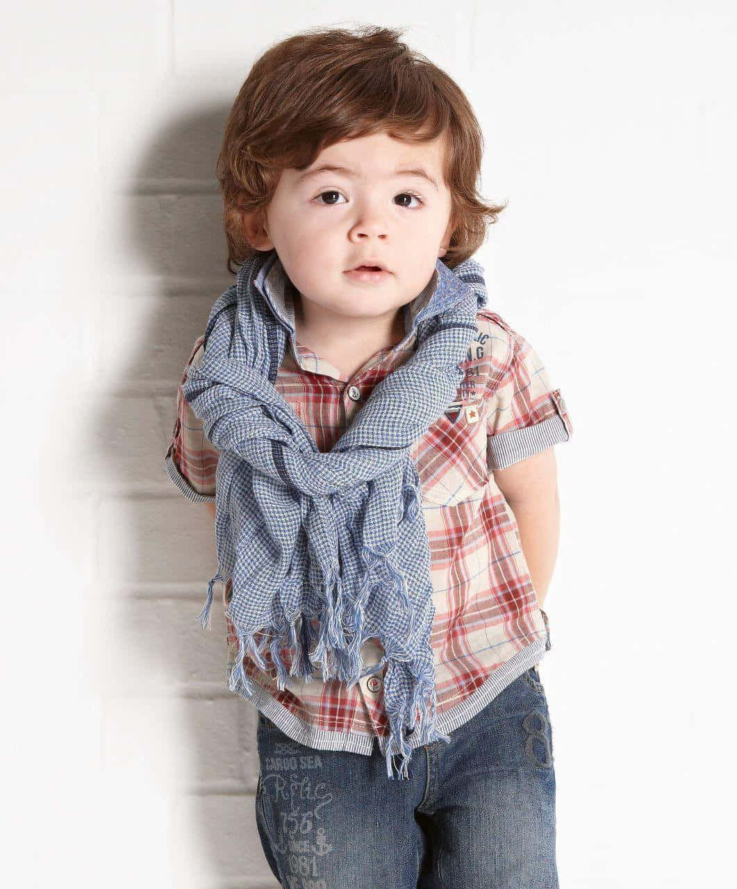Cute Boy 桌布 壁紙 — 一個棕色頭髮的小孩穿著格紋襯衫和藍色圍巾，站在白色磚牆前。
