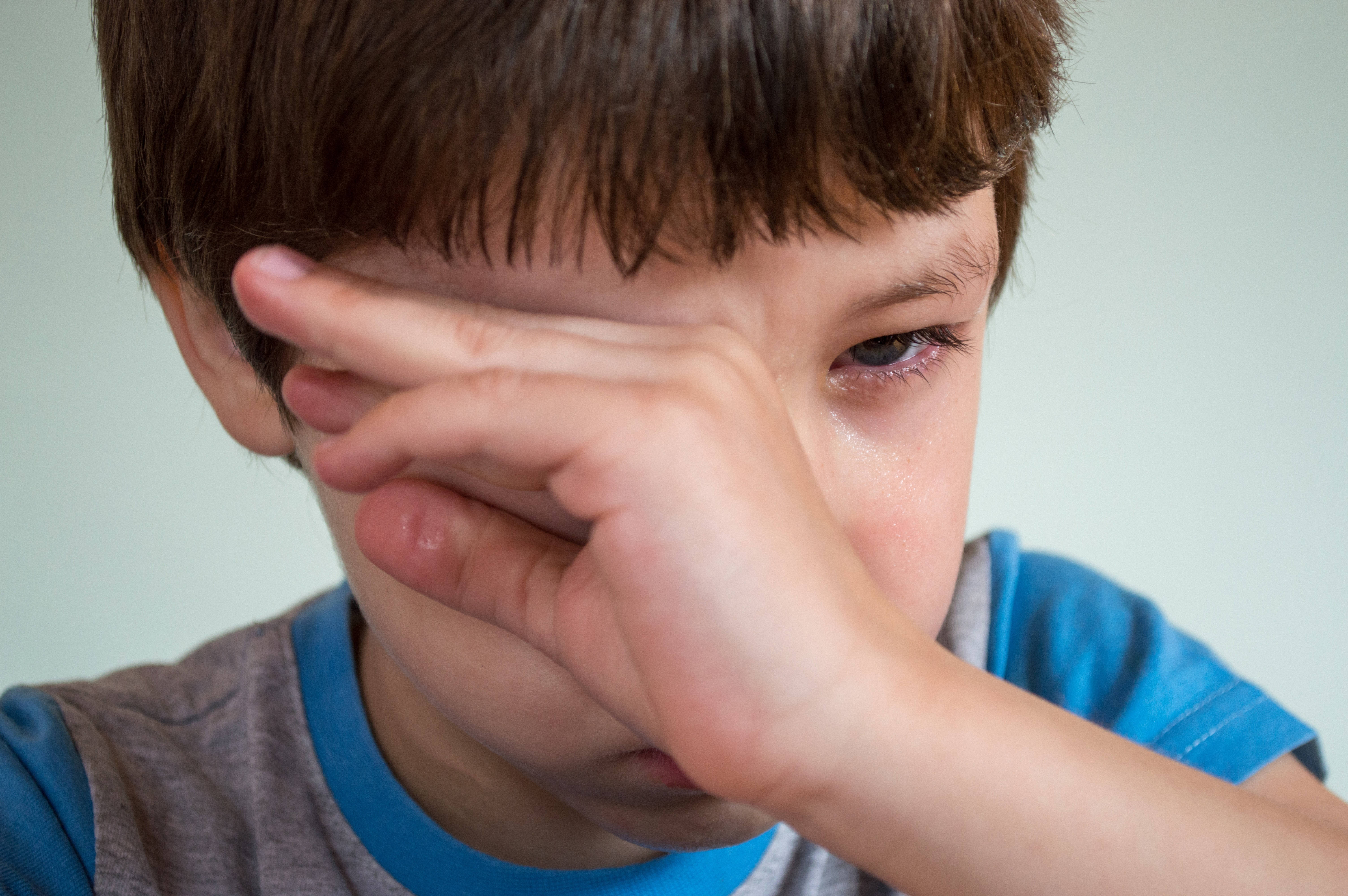 crying sad boy 桌布 壁紙 — 一個棕色頭髮的小男孩用手遮住眼睛，淚水順著臉頰流下，背景是純色淺色。