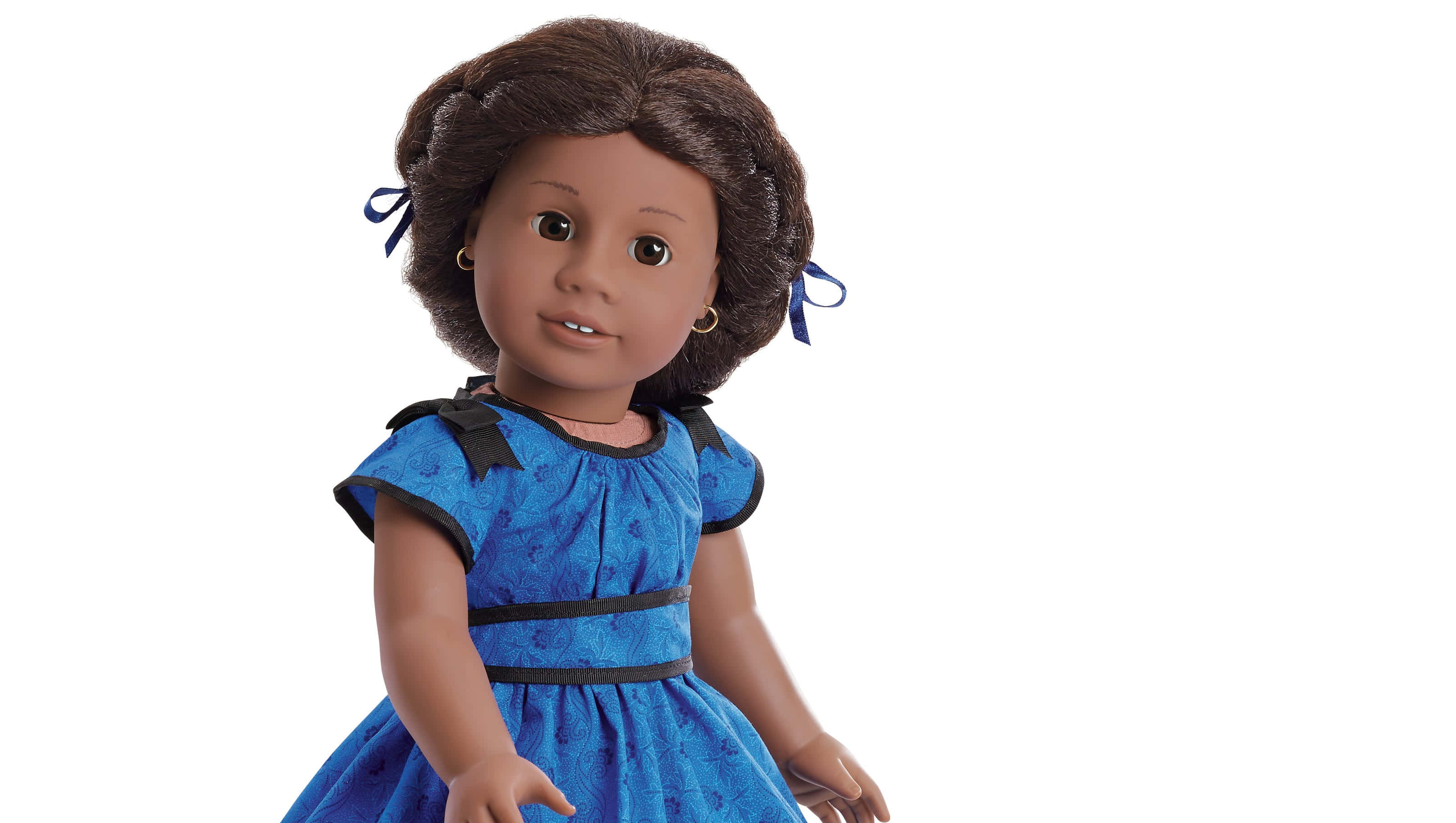 american girl 桌布 壁紙 — 一個棕色頭髮編成辮子並飾有藍色絲帶的娃娃，穿著帶黑色飾邊的藍色圖案連衣裙，背景為純白色。