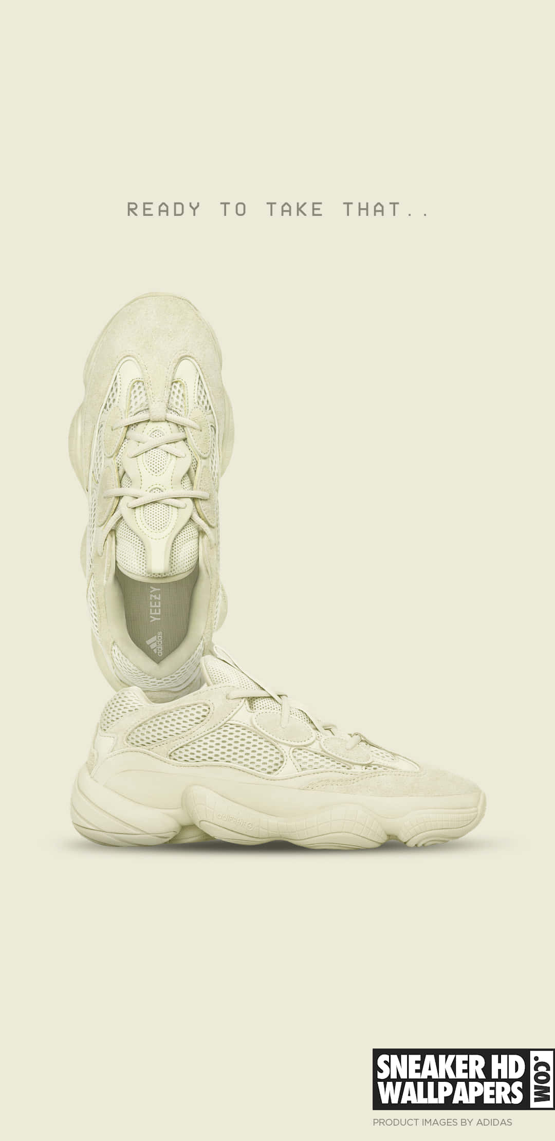 Yeezy 桌布 壁紙 — 一個極簡主義的攝影棚拍攝，兩雙米白色Yeezy運動鞋垂直堆疊在淺米色背景上，帶有模糊文字。