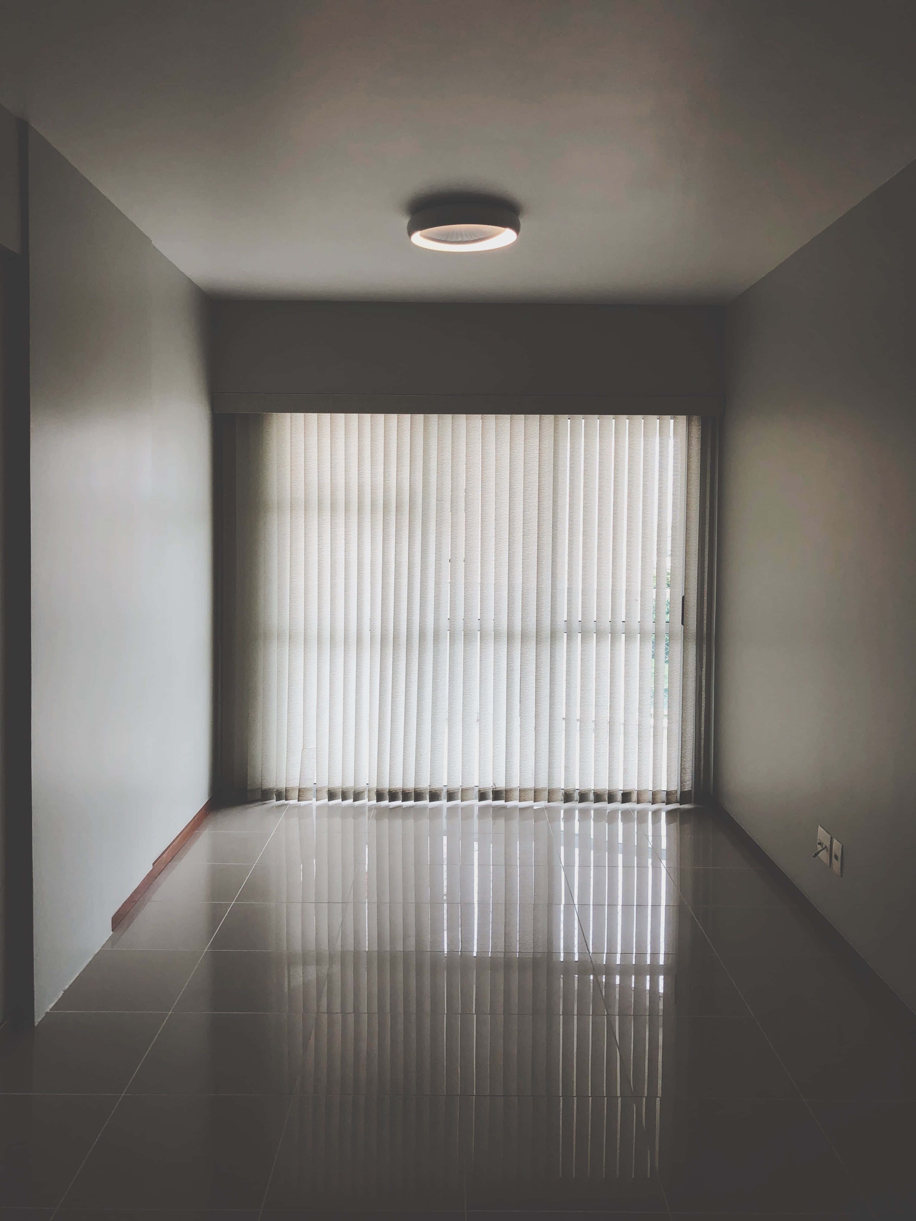 Empty Room 桌布 壁紙 — 一個極簡主義的空房間，光滑的瓷磚地板反射著垂直百葉窗和單一吊燈。