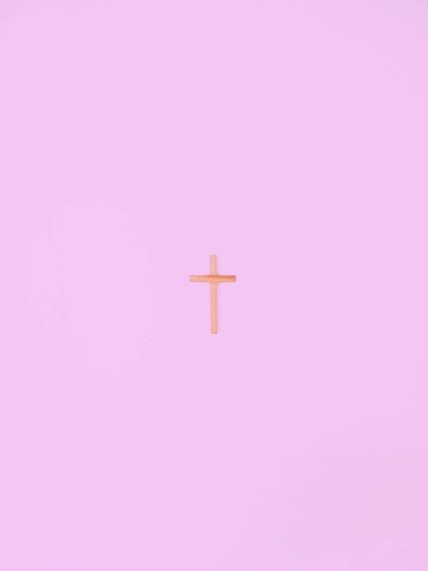 Cute Cross 桌布 壁紙 — 一個極簡木製十字架，置中於柔和粉紅漸變背景上，帶有細微的光暈。