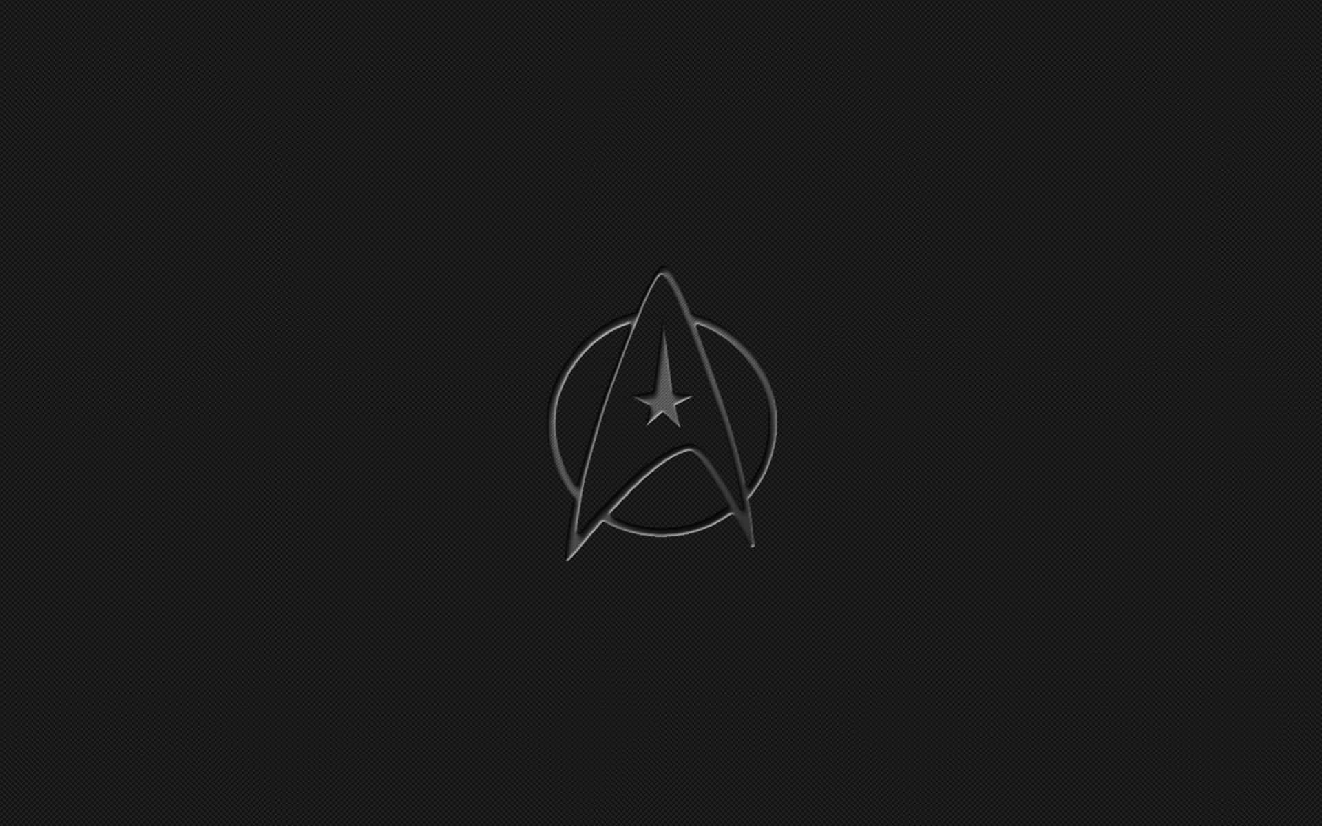 星際爭霸戰 桌布 壁紙 — 一個極簡的星際艦隊徽章在帶有紋理的黑色背景上微微發光。