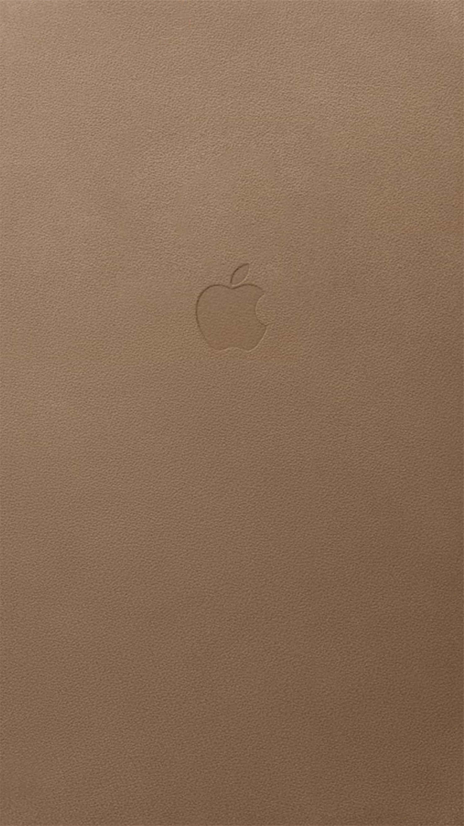 Tan 桌布 壁紙 — 一個極簡的棕褐色皮革表面，中央帶有微妙的壓印Apple標誌。