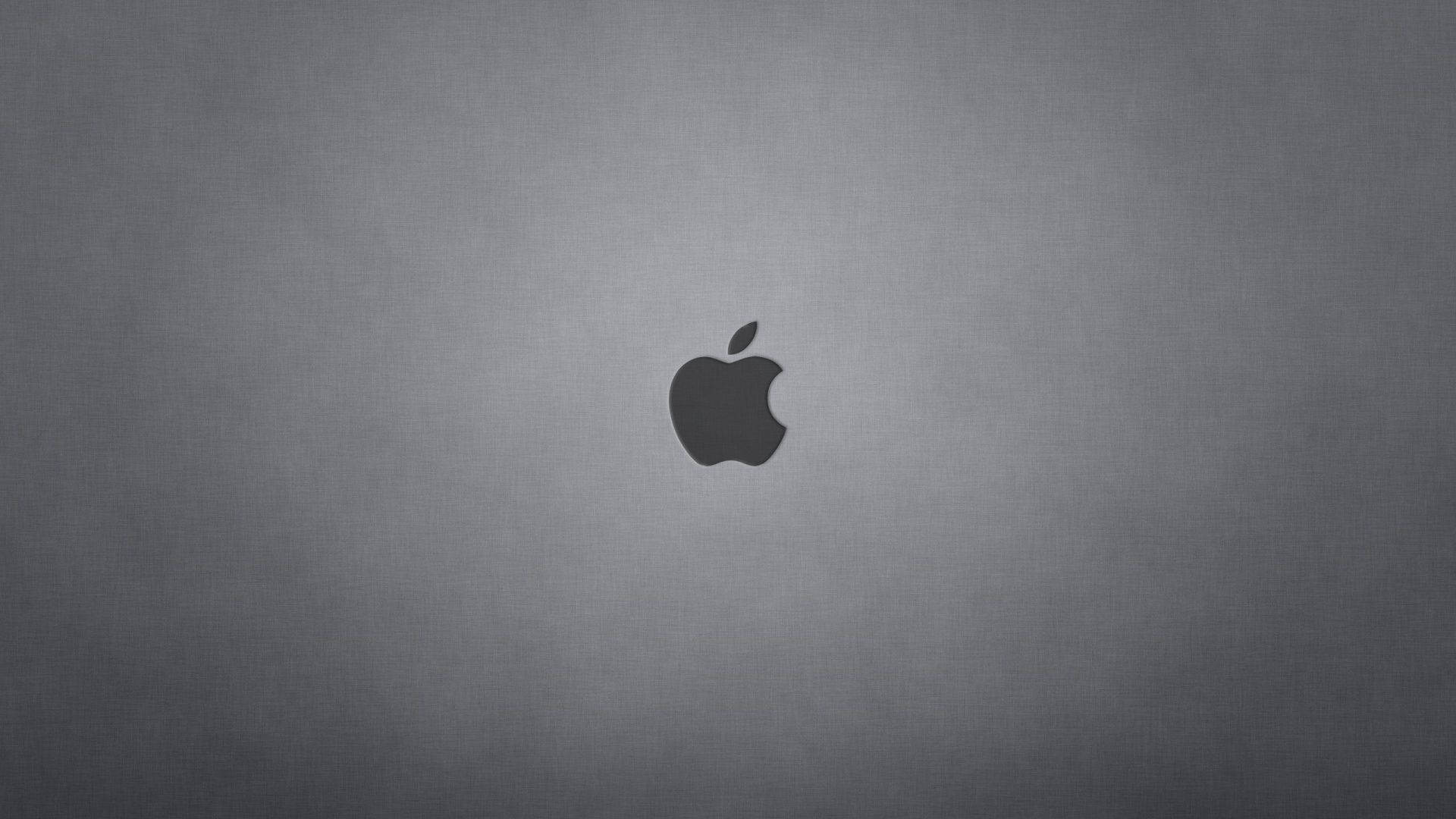 Mac 桌布 壁紙 — 一個極簡的深灰色Apple標誌，居中放置在帶有微妙紋理的漸變背景上。