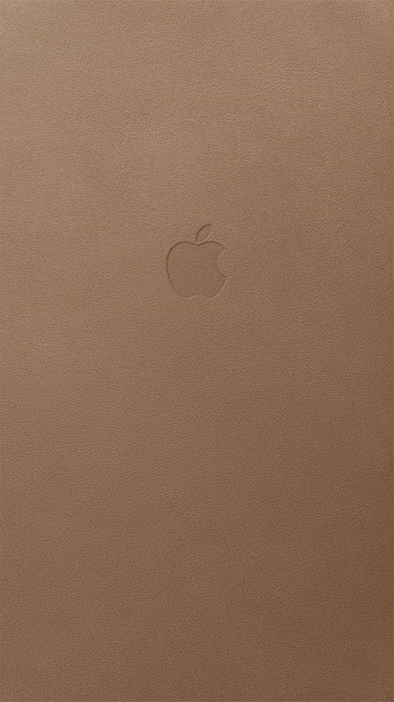 Brown iPhone 桌布 壁紙 — 一個極簡的淺棕色皮革表面，中央有一個微妙的壓印 Apple 標誌。