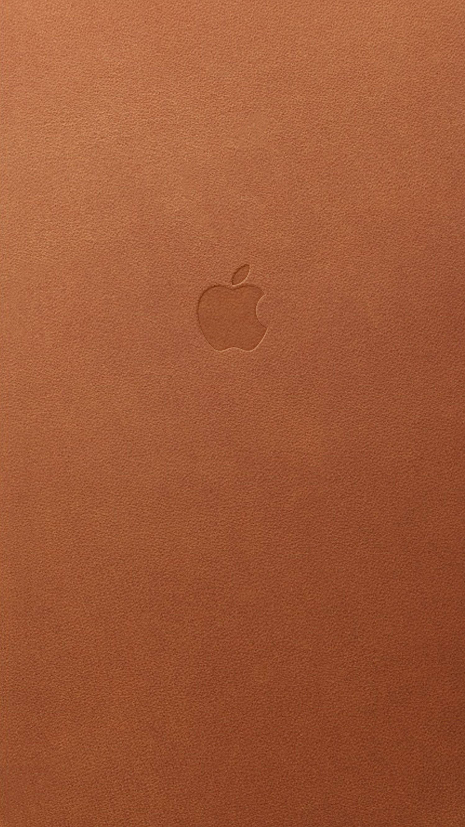 Tan 桌布 壁紙 — 一個極簡的特寫，Apple 標誌微妙地壓印在豐富的棕色皮革紋理上。