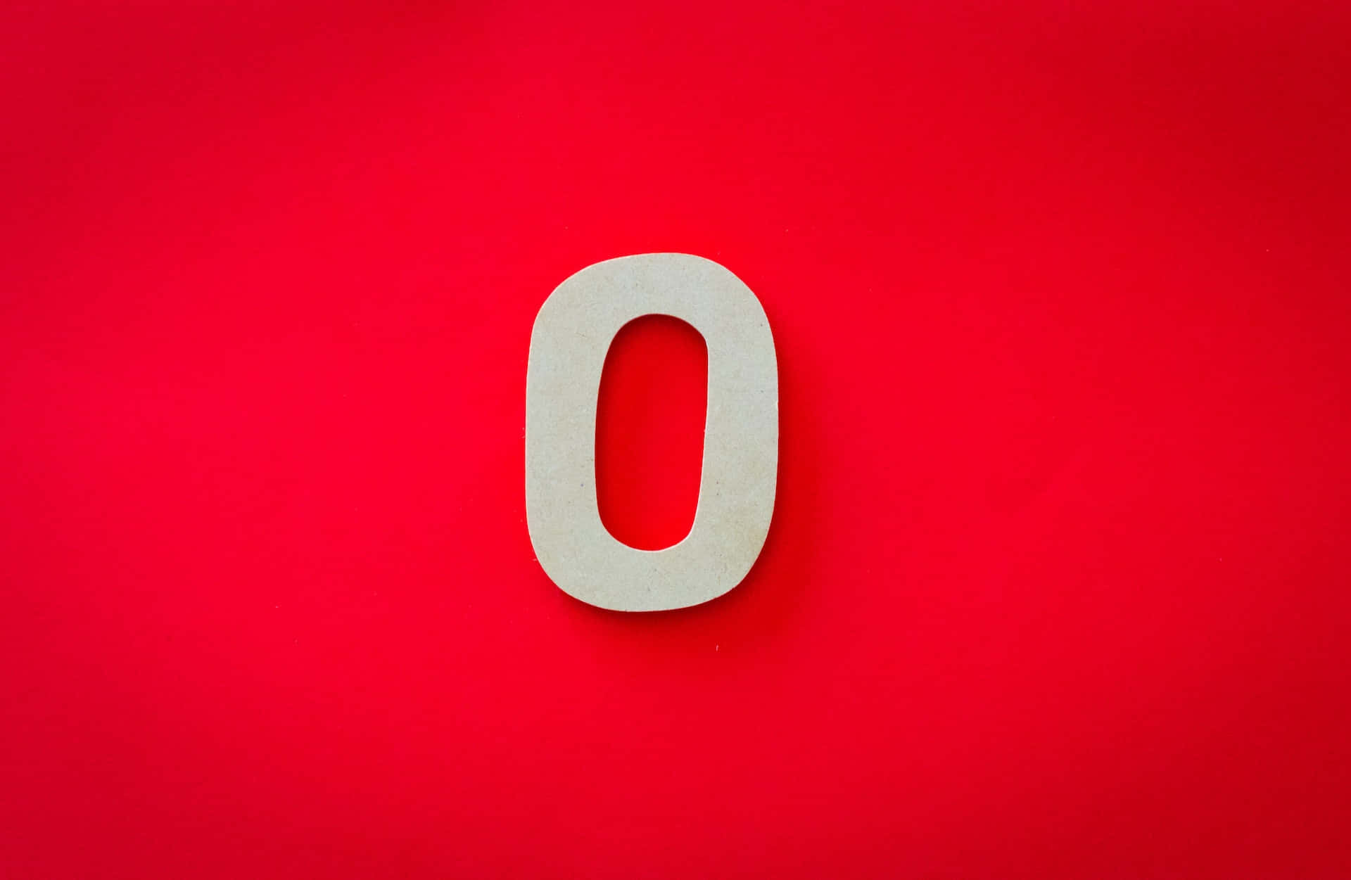 Number 桌布 壁紙 — 一個極簡的米色鏤空字母O，居中放置在鮮豔的純紅色背景上。