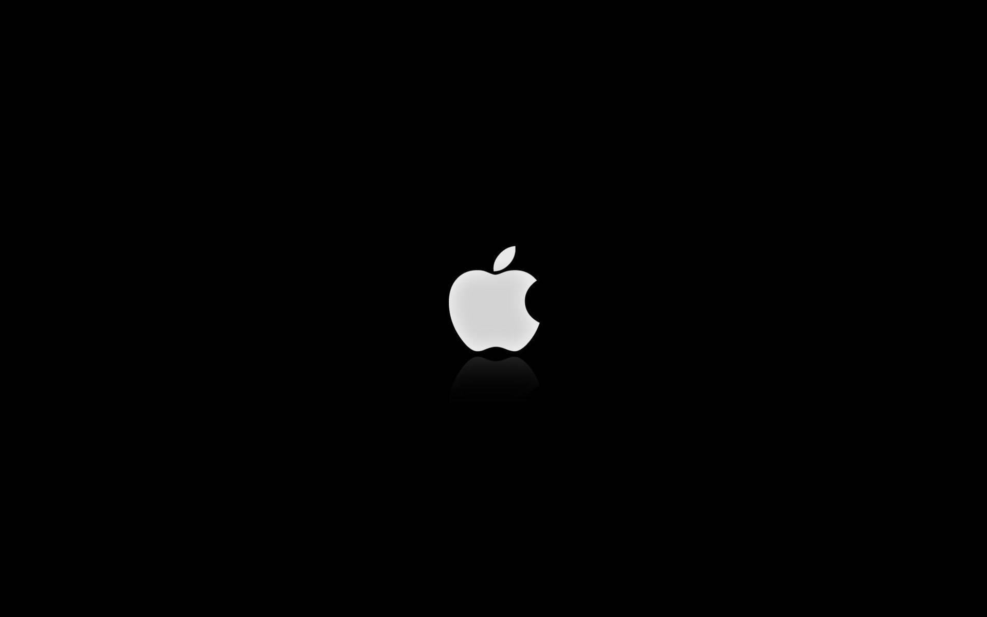 蘋果 桌布 壁紙 — 一個極簡的銀色Apple標誌，居中於純黑色背景上，下方帶有微妙的倒影。