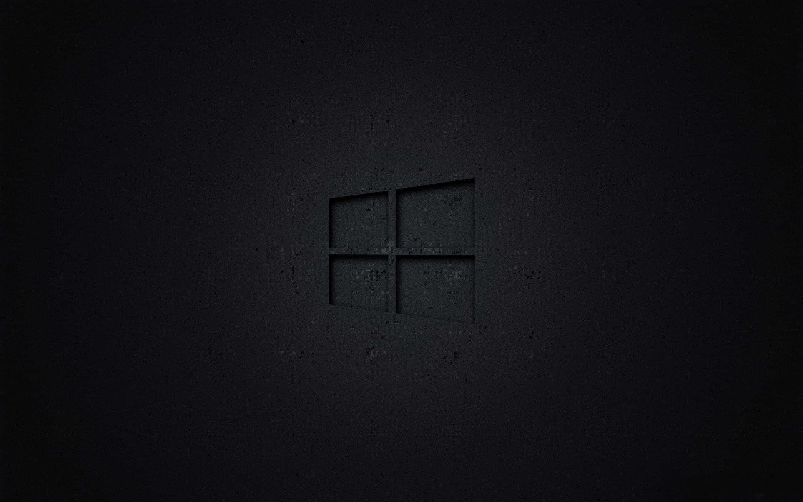 極簡美學 桌布 壁紙 — 一個極簡的黑色Windows標誌，在柔和的燈光下微妙地壓印在霧面深色表面上。