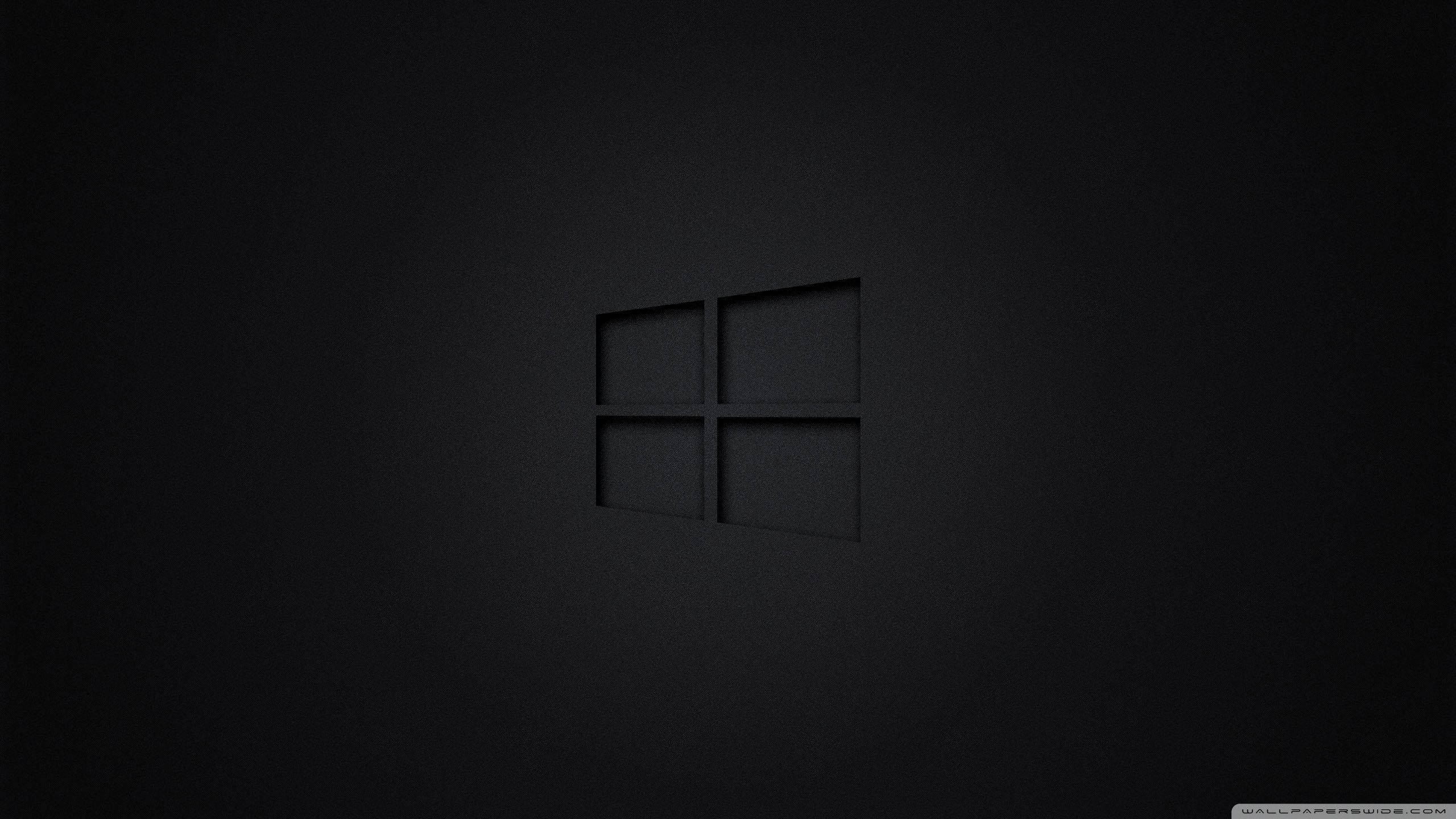 暗色電腦 桌布 壁紙 — 一個極簡的黑色Windows標誌，在帶有柔和照明的紋理深色表面上低調壓印。