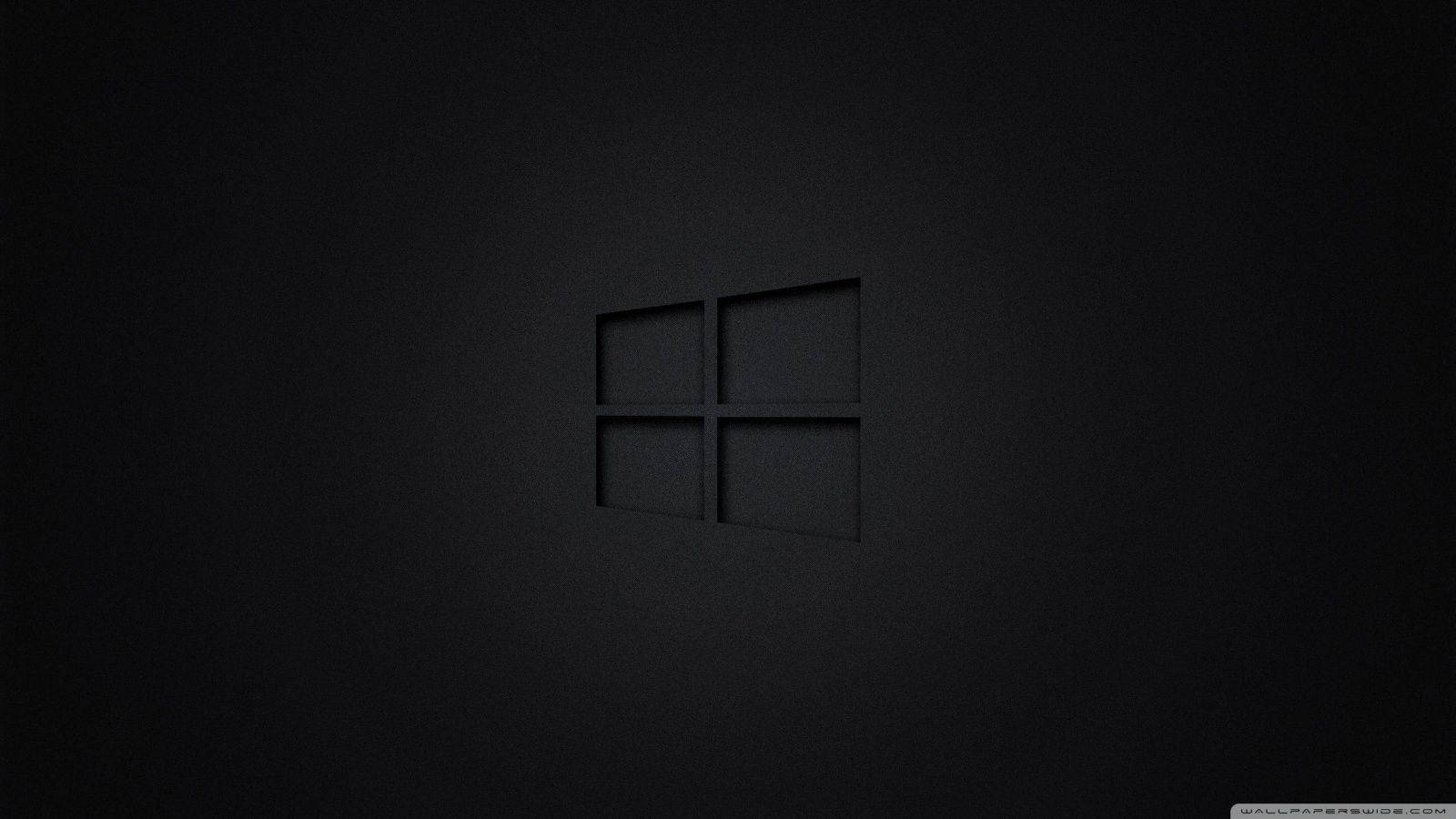 黑色 桌布 壁紙 — 一個極簡的黑色Windows標誌，在帶有紋理的深色表面上以柔和光線呈現微妙的浮雕效果。