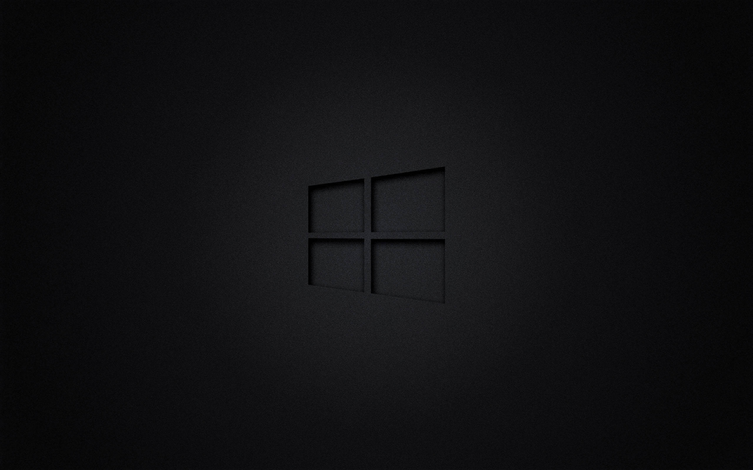 Chrome 桌布 壁紙 — 一個極簡的黑色Windows標誌，在帶有紋理的深色表面上以柔和光線微妙地壓印。