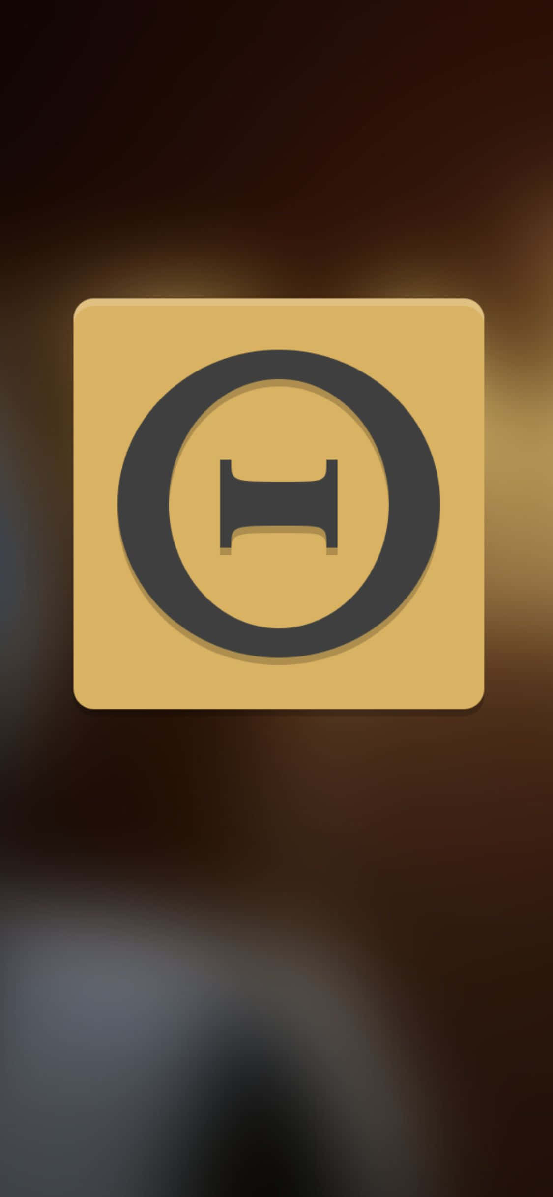 iPhone Xs The Talos Principle 桌布 壁紙 — 一個極簡金色方形圖示，中央有一個黑色圓形H符號，背景為模糊的暖色漸層。