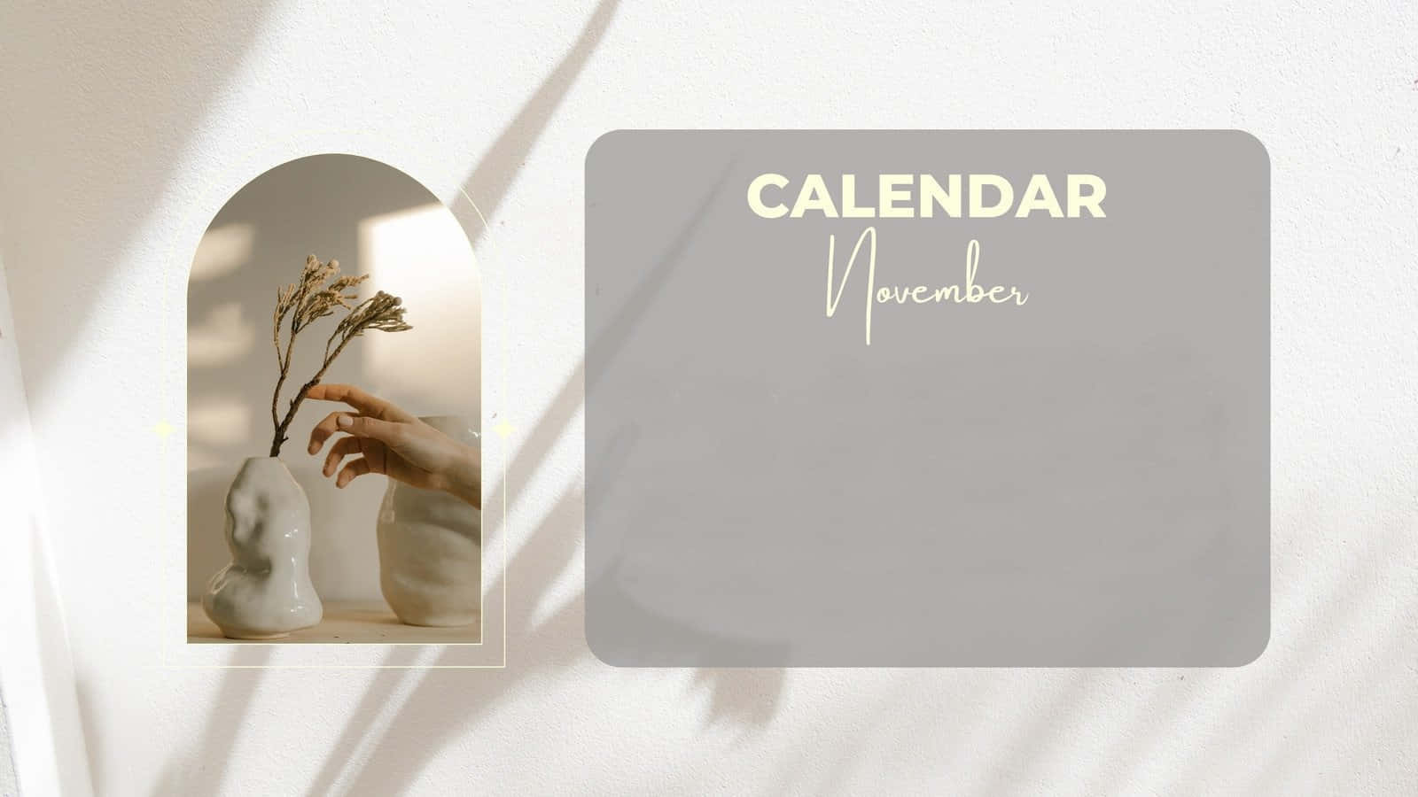 Aesthetic November 桌布 壁紙 — 一個極簡風格的十一月日曆，旁邊是一隻手輕輕觸摸雕塑花瓶中的乾燥花，花瓶沐浴在柔和陽光下。