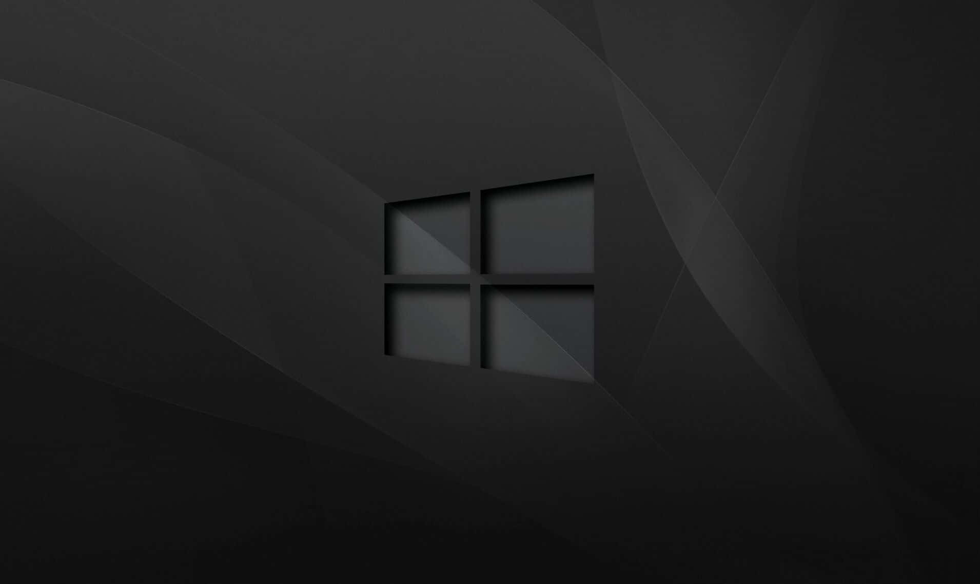 Windows 10 Desktop 桌布 壁紙 — 一個極簡風格的深灰色抽象背景，中央有一個微妙的浮雕Windows標誌，位於柔和的幾何摺痕中。