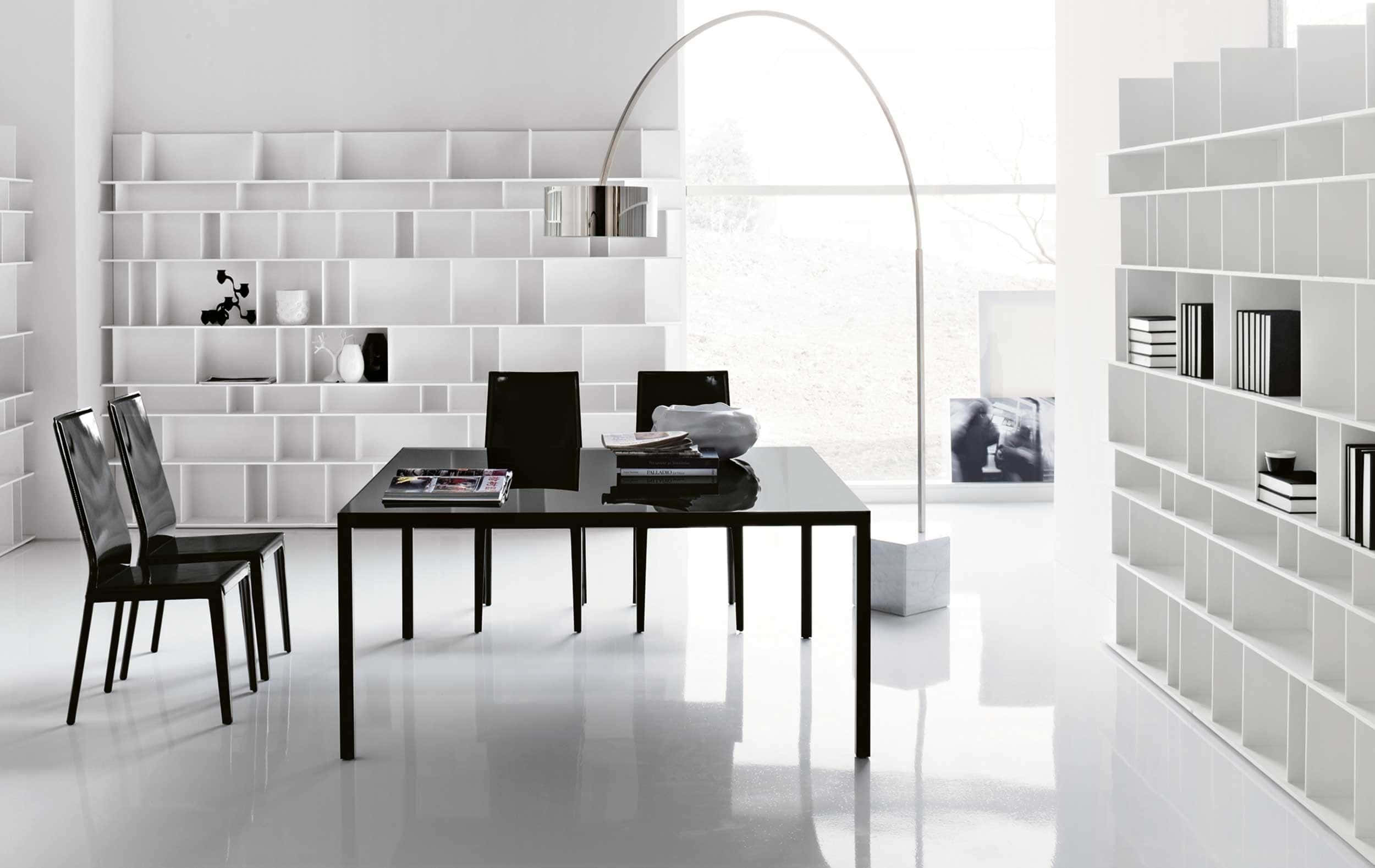 Modern Office 桌布 壁紙 — 一個極簡風格的用餐區，配有黑色家具和白色模組化層架，沐浴在明亮的自然光中。