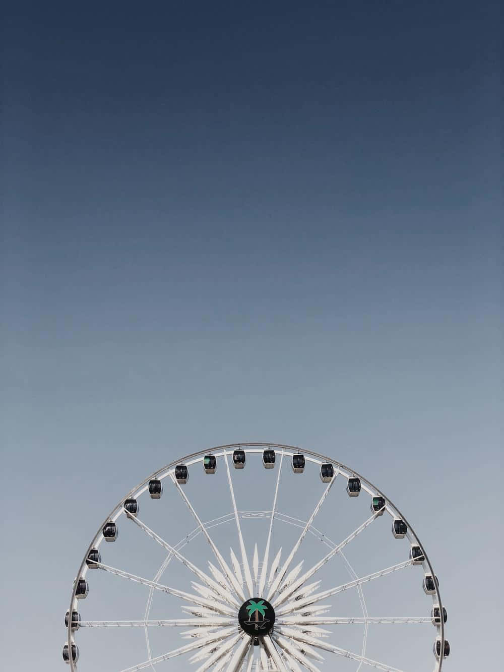 Coachella 桌布 壁紙 — 一個極簡風格的白色摩天輪，帶有棕櫚樹標誌，矗立在漸變藍色天空前。