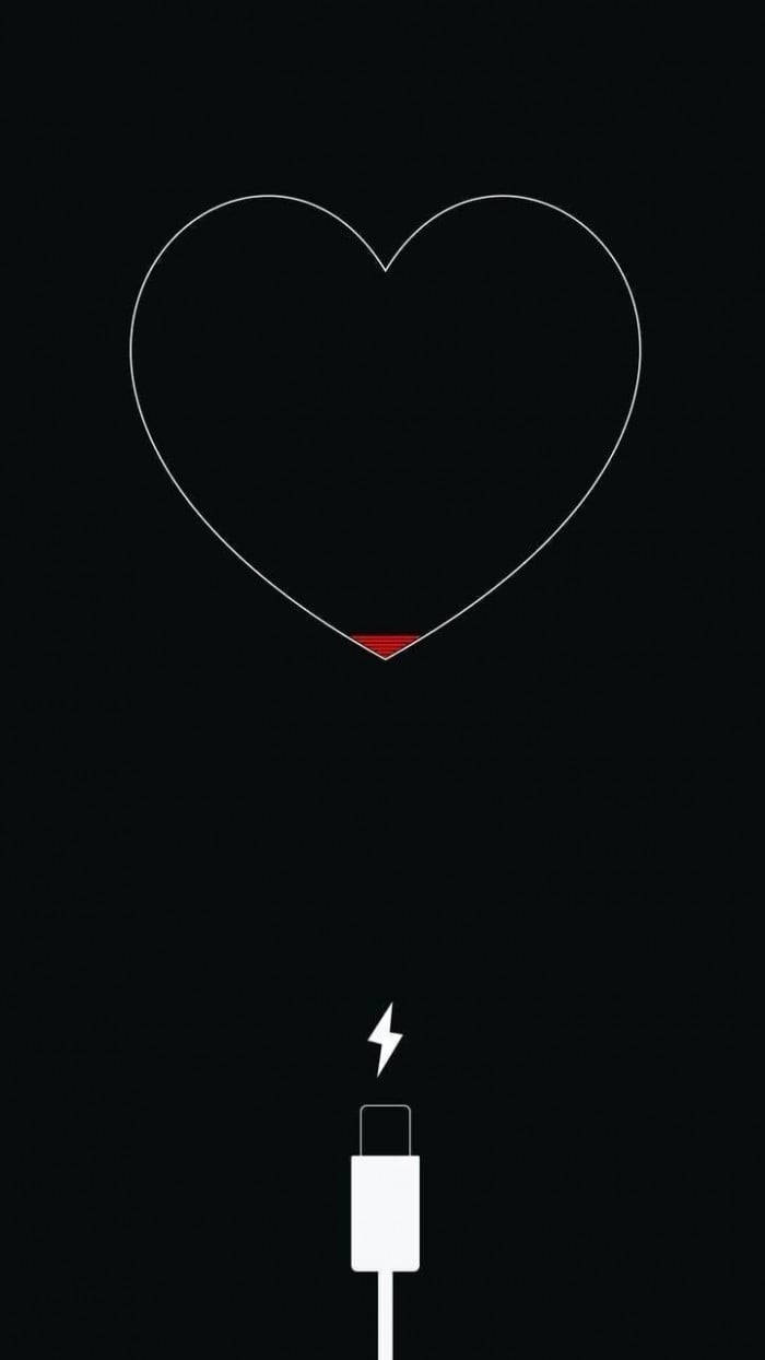 Broken Heart iPhone 桌布 壁紙 — 一個極簡風格的白色輪廓心形，底部有紅色充電指示燈，正在被一條白色USB線在黑色背景上充電。