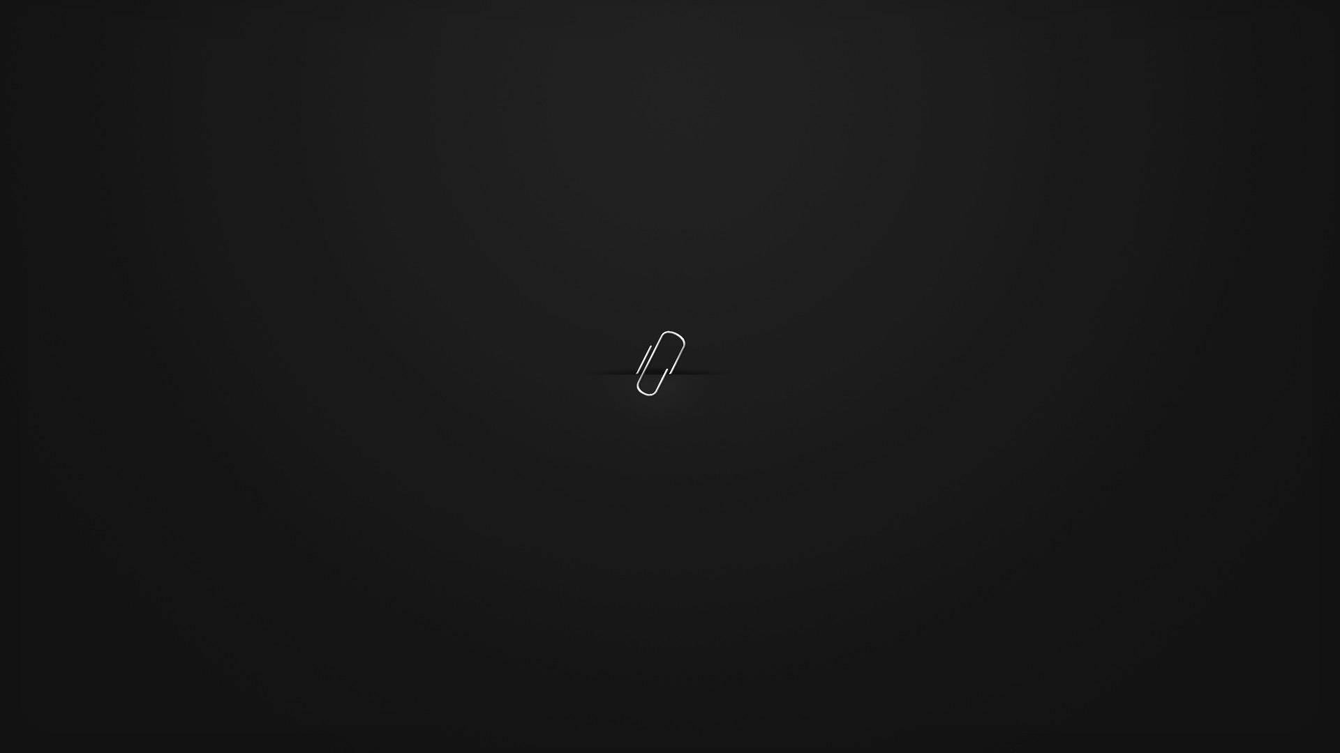 Dark Minimalist 桌布 壁紙 — 一個極簡風格的白色迴紋針圖示，置中於帶柔和照明的深色漸變背景上。