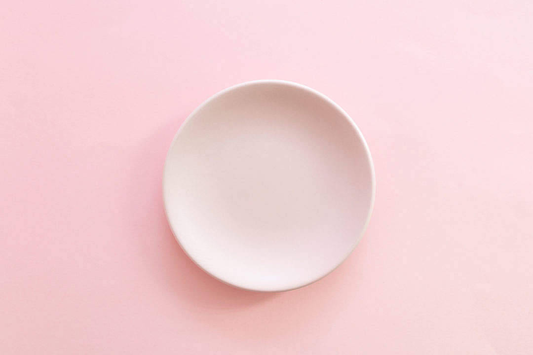 Pastel Pink Aesthetic 桌布 壁紙 — 一個極簡風格的白色陶瓷盤，置於柔和的粉紅色背景中央，帶有柔和陰影。