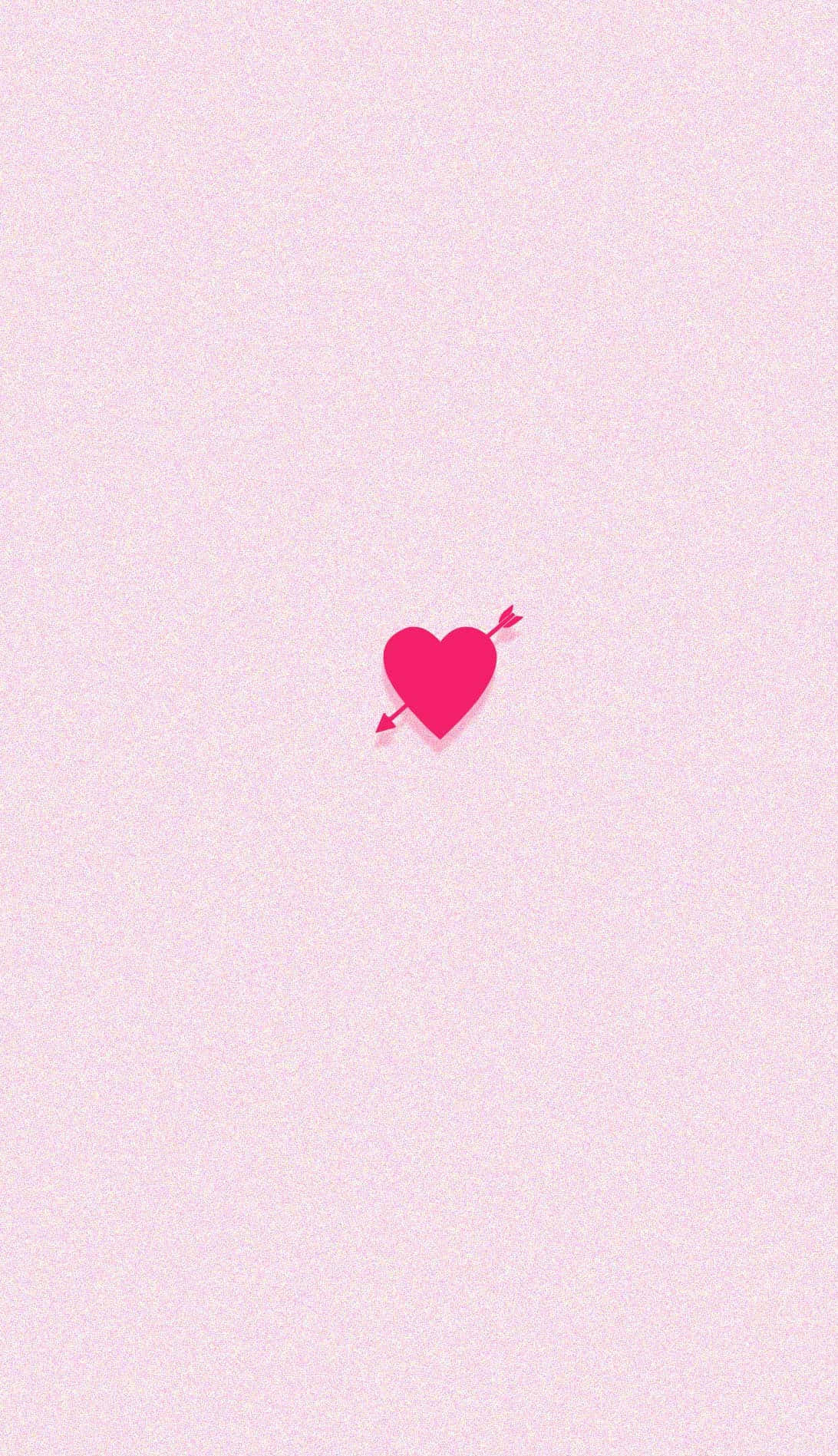 Valentines 桌布 壁紙 — 一個極簡風格的粉紅色心形，被一支小箭穿過，置中在柔軟紋理的淺粉紅色背景上。