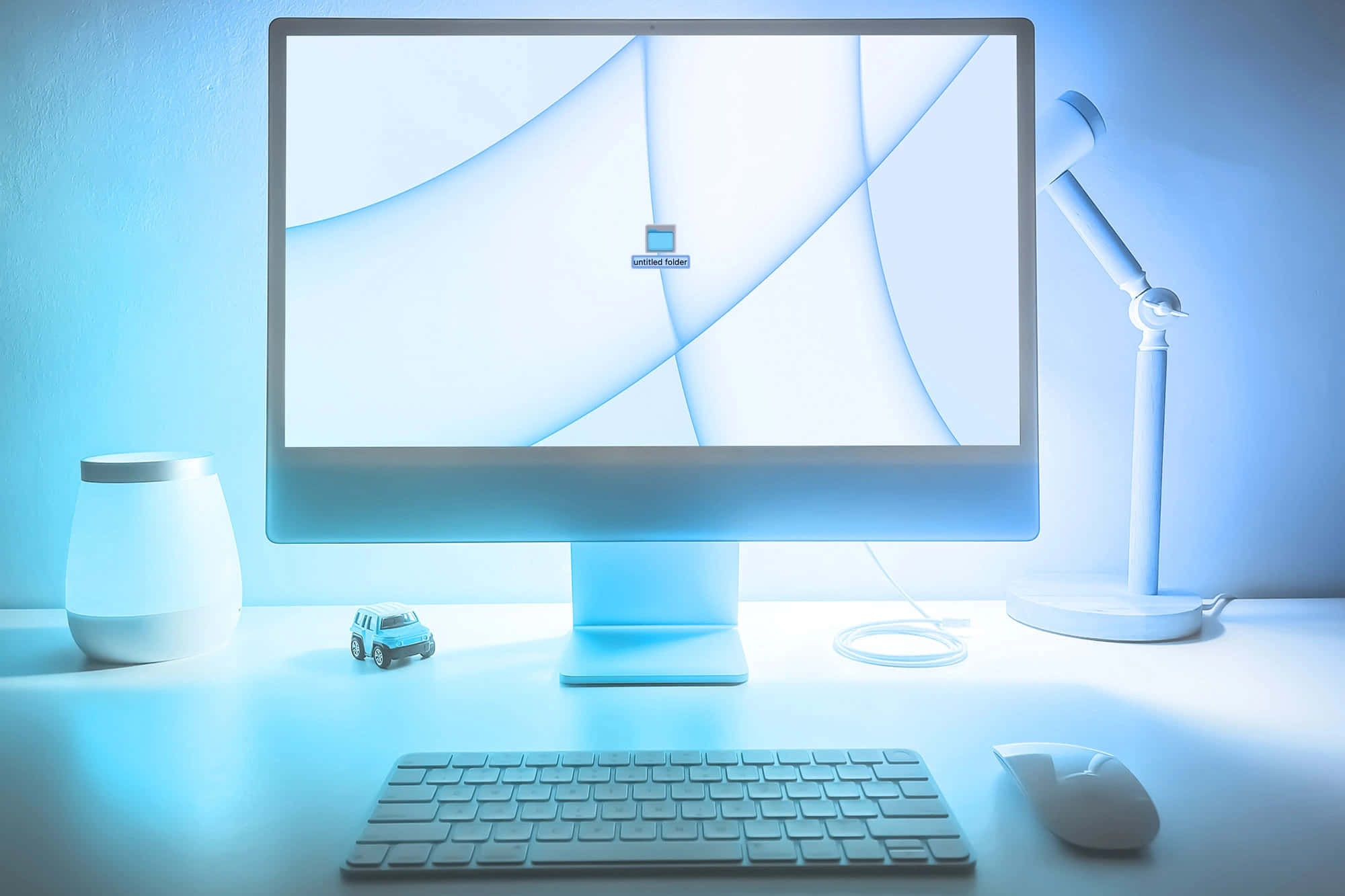 Computer Monitor 桌布 壁紙 — 一個極簡風格的辦公桌設置，沐浴在冷藍光中，配有纖薄顯示器、鍵盤、滑鼠和一個小汽車模型。