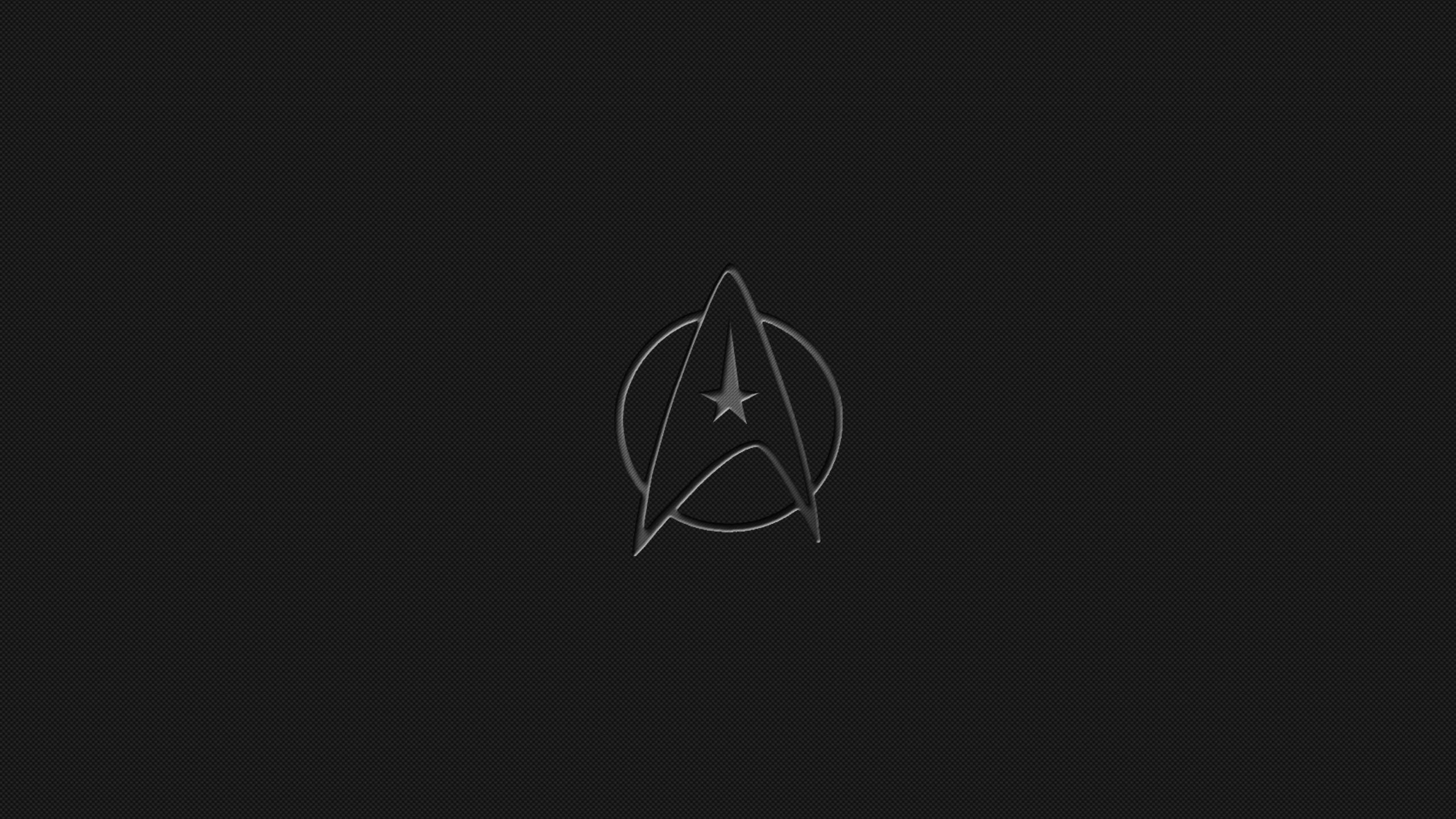 星際爭霸戰 桌布 壁紙 — 一個極簡風格的銀色星際艦隊徽章在帶紋理的黑色背景上微微發光。