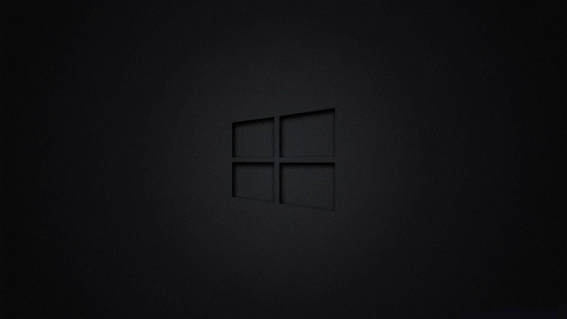 黑色 Windows 10 桌布 壁紙 — 一個極簡風格的黑色Windows標誌，在帶有柔和光線的紋理深色表面上低調壓印。