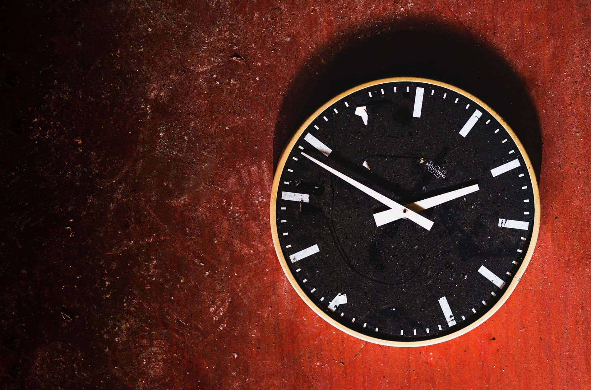 Wall Clock 桌布 壁紙 — 一個極簡風格的黑色時鐘，帶有白色指針和刻度，掛在帶有紋理的深紅色牆壁上，投下柔和的陰影。
