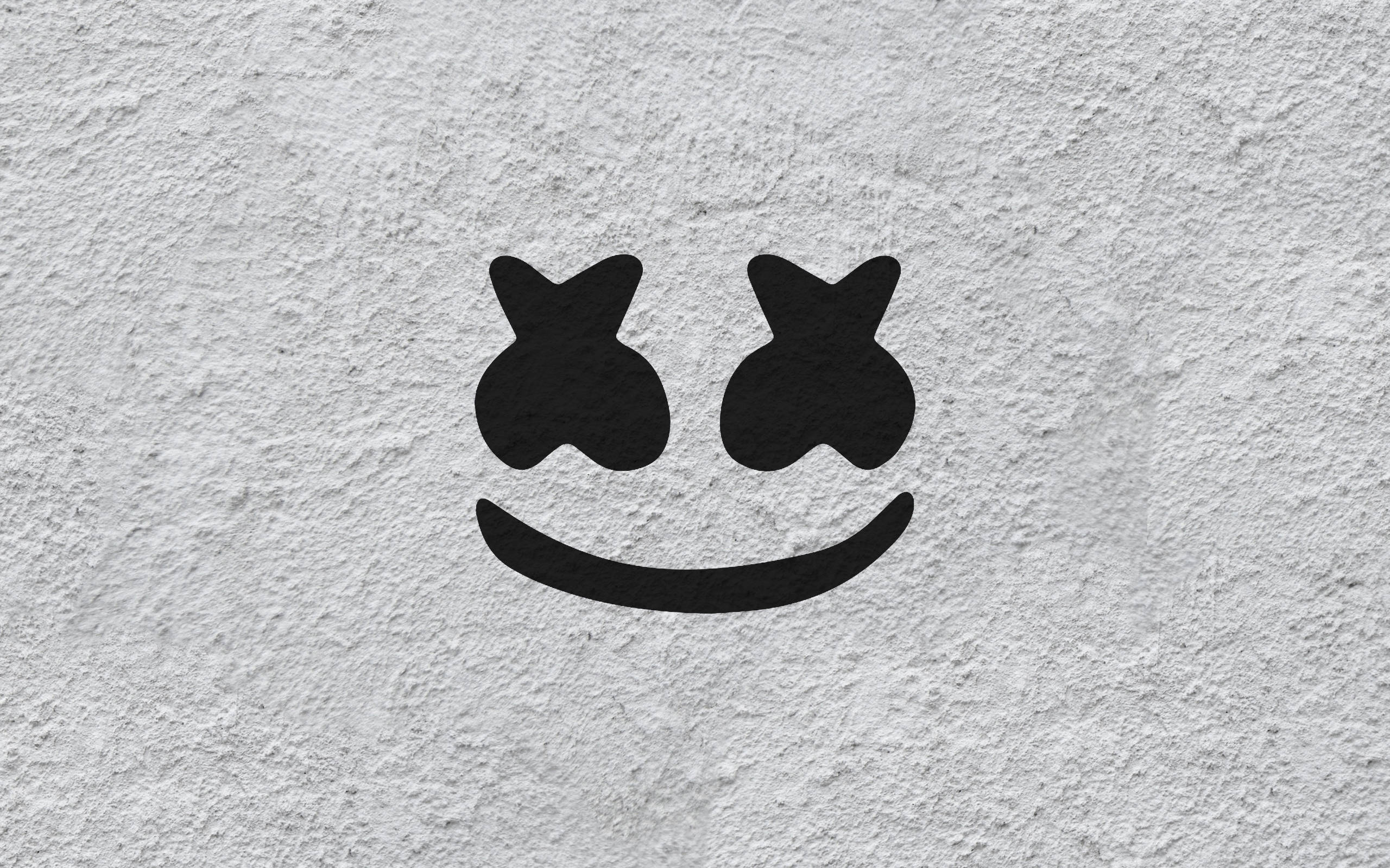 Marshmello 動態圖 桌布 壁紙 — 一個極簡風格的黑色笑臉，帶有星形眼睛，畫在粗糙紋理的白色牆壁上。