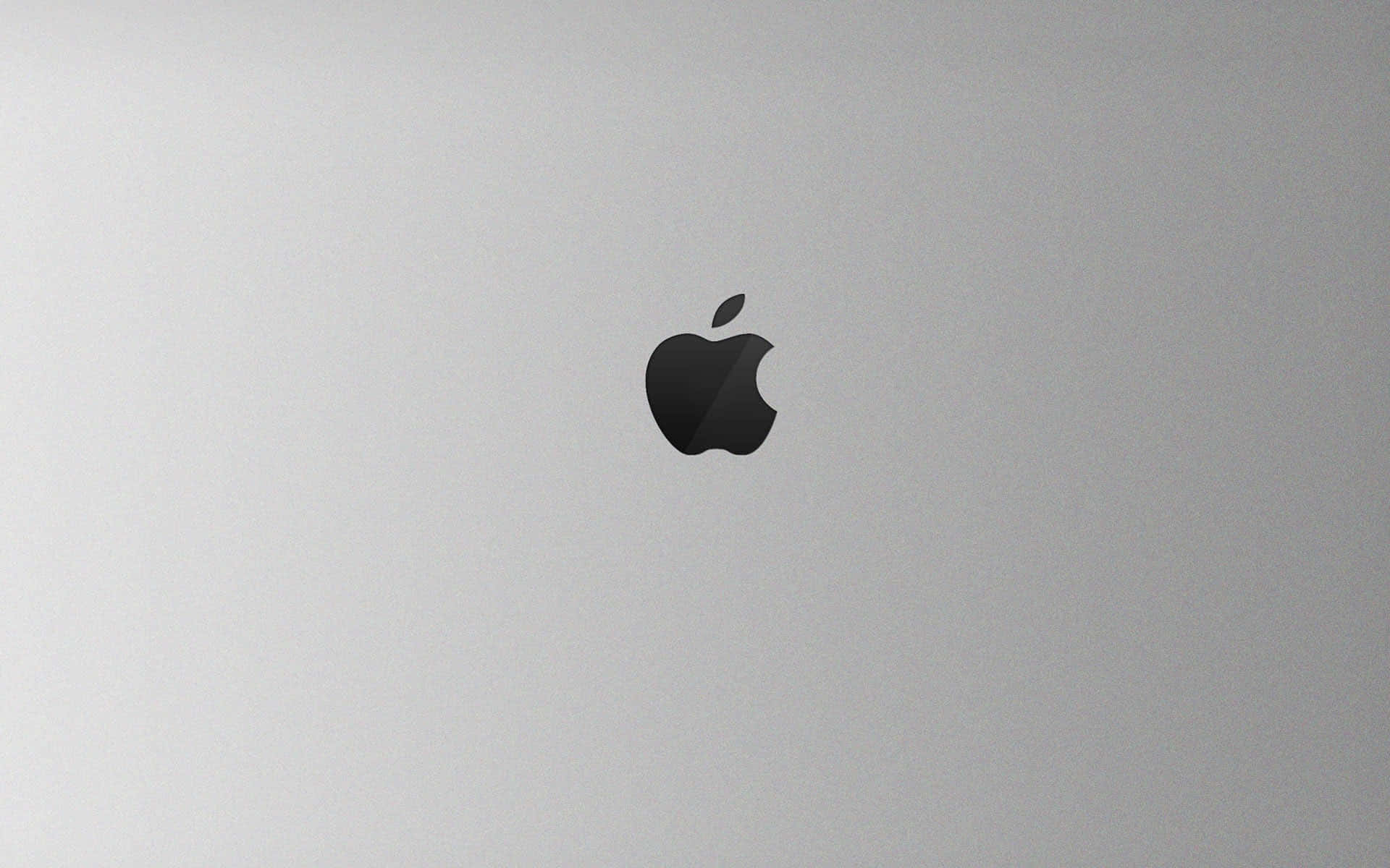蘋果 桌布 壁紙 — 一個極簡黑色Apple標誌，居中於拉絲銀色筆記型電腦蓋上，帶柔和燈光。