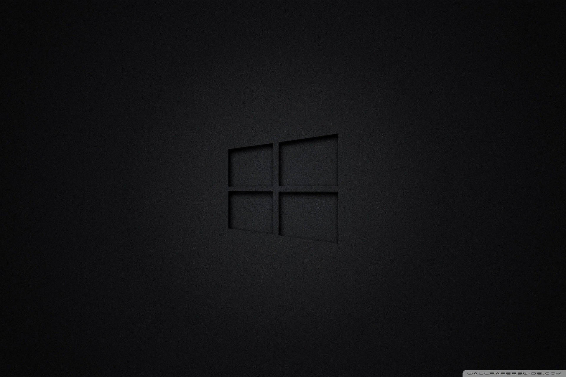 Windows標誌壓印在啞光深色表面上，柔和燈光。 — Microsoft 壁紙