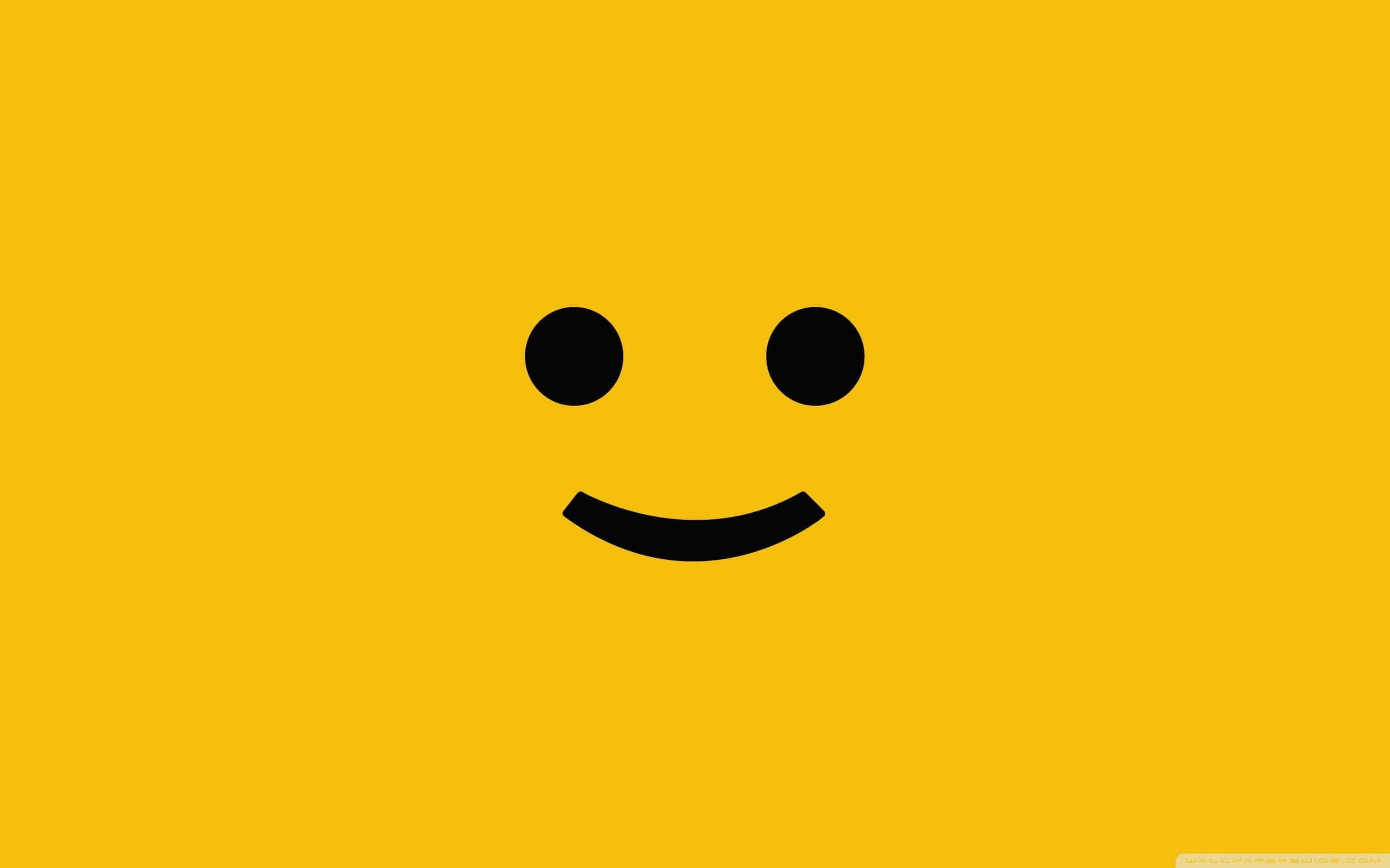 Aesthetic Smiley Face 桌布 壁紙 — 一個極簡黑色笑臉，居中在純亮黃色背景上。