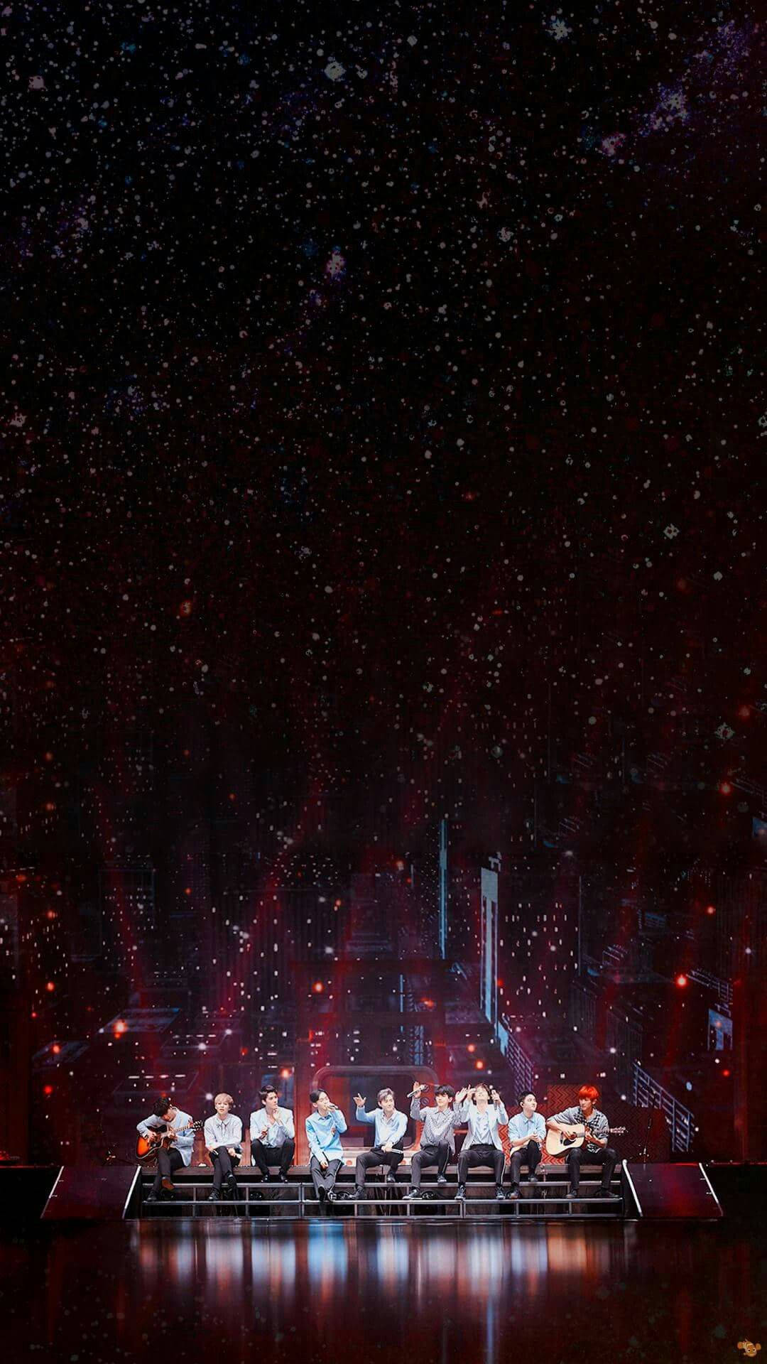 EXO 桌布 壁紙 — 一個樂團在星空宇宙背景下，紅色燈光和飄落的雪花中在舞台上表演。