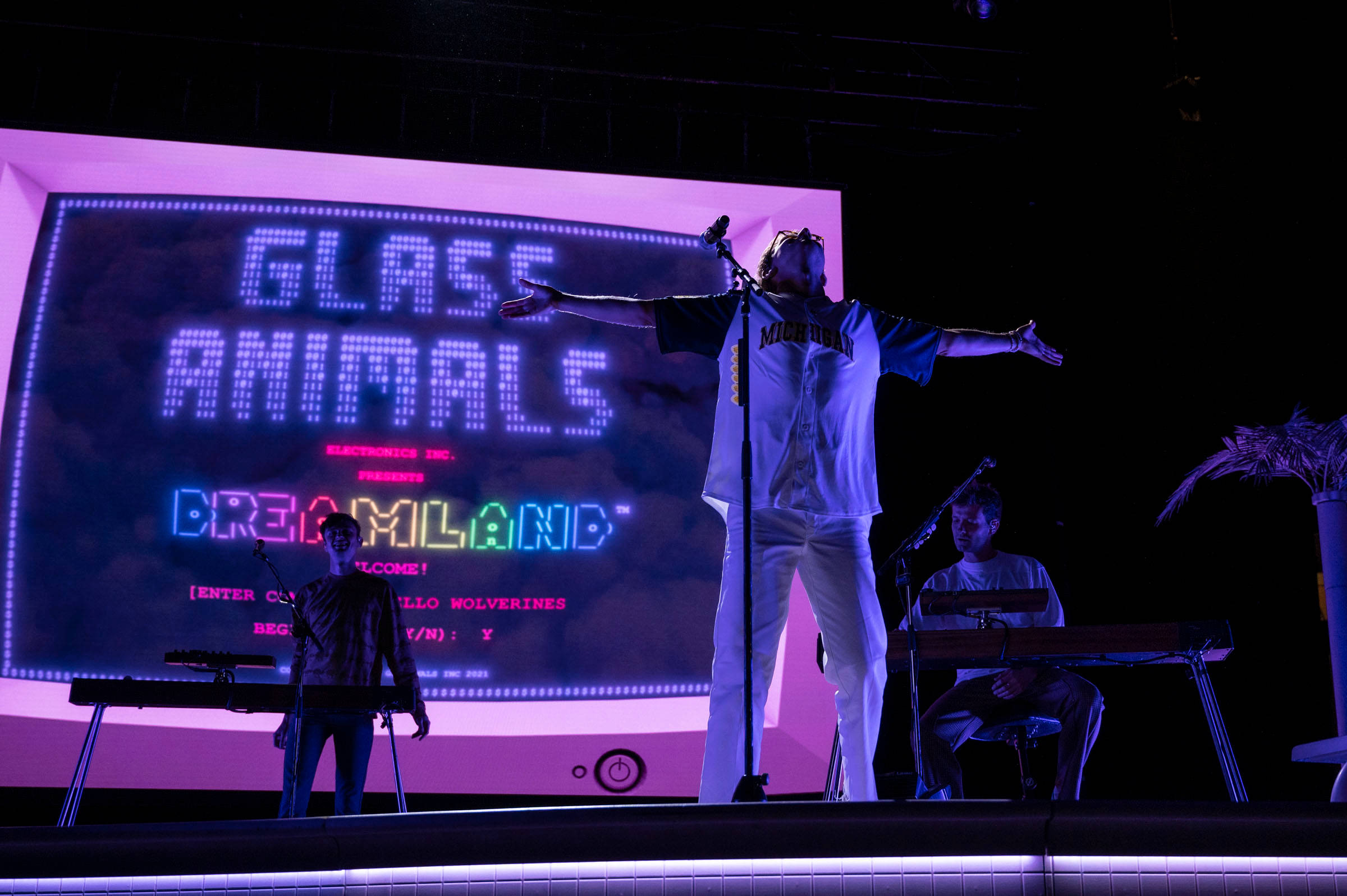 animals 桌布 壁紙 — 一個樂團在黑暗的舞台上，紫色燈光下表演，身後有一個大螢幕顯示「GLASS ANIMALS DREAMLAND」。