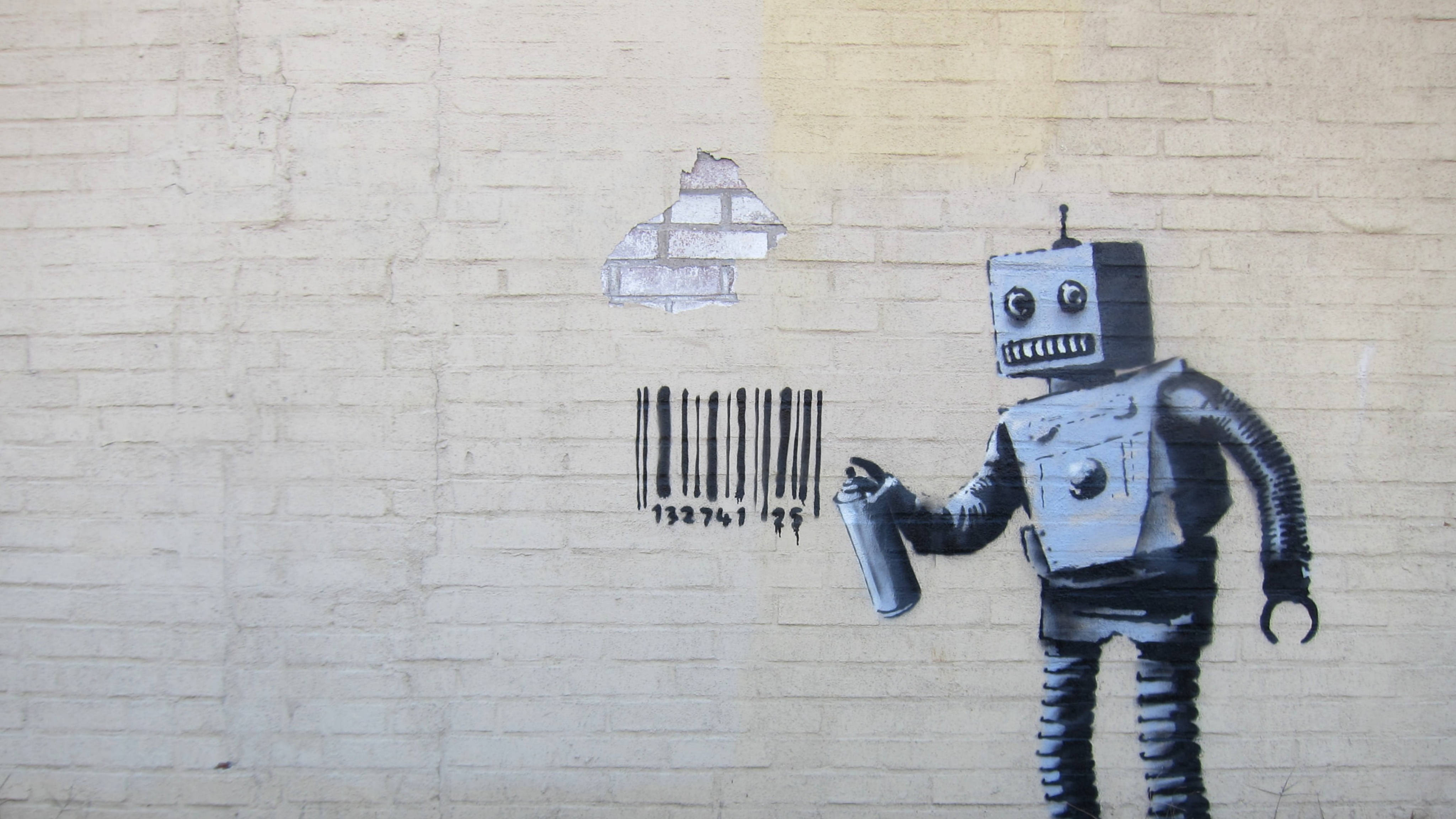 Banksy 桌布 壁紙 — 一個模板塗鴉機器人在風化的磚牆上噴上條碼和碎磚。