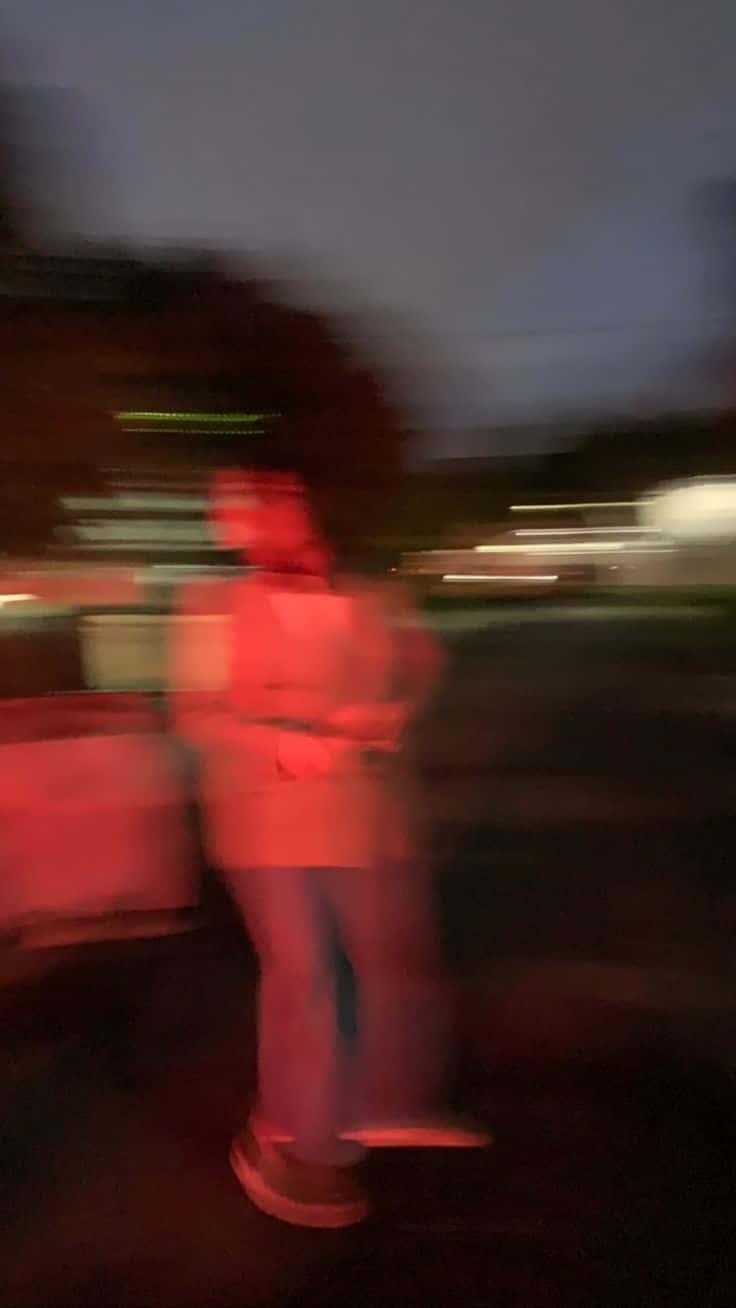 Man 桌布 壁紙 — 一個模糊的身影在紅色霓虹燈光下靜止不動，背景是帶有條紋的城市夜景。