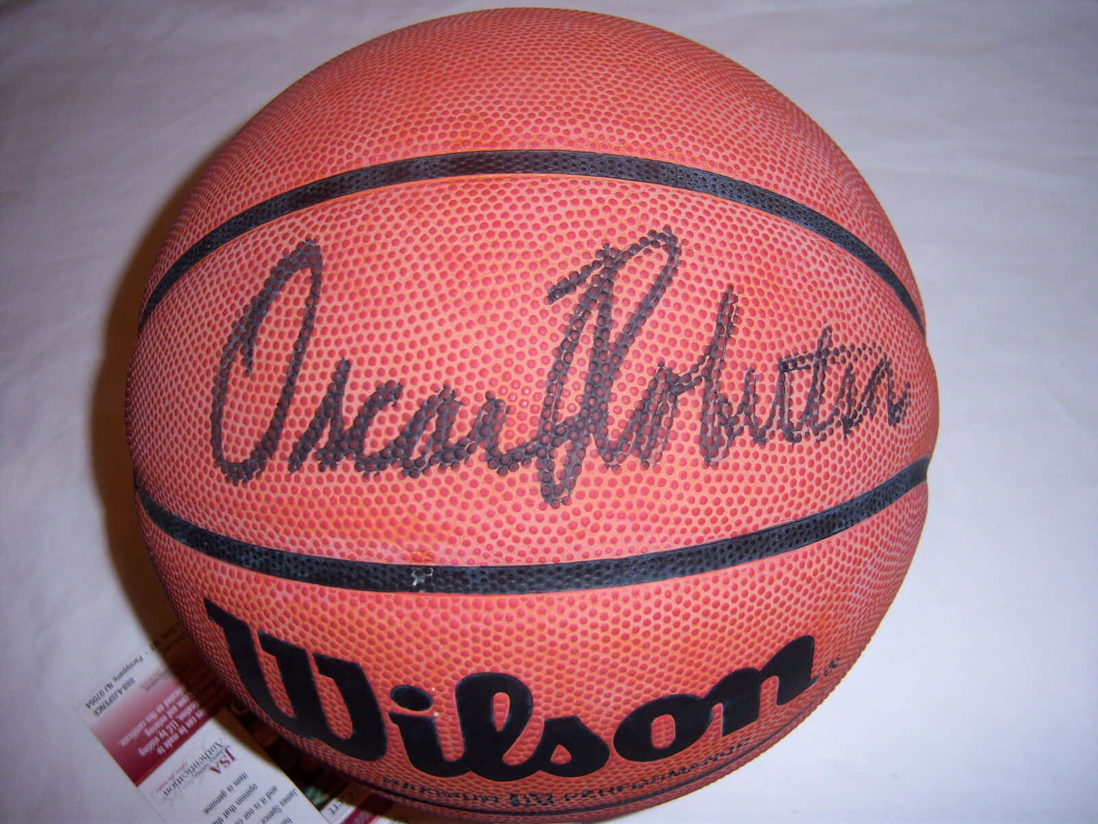 sign 桌布 壁紙 — 一個橙色Wilson籃球的特寫，上面有黑色簽名寫著Oscar Robertson，背景為白色。