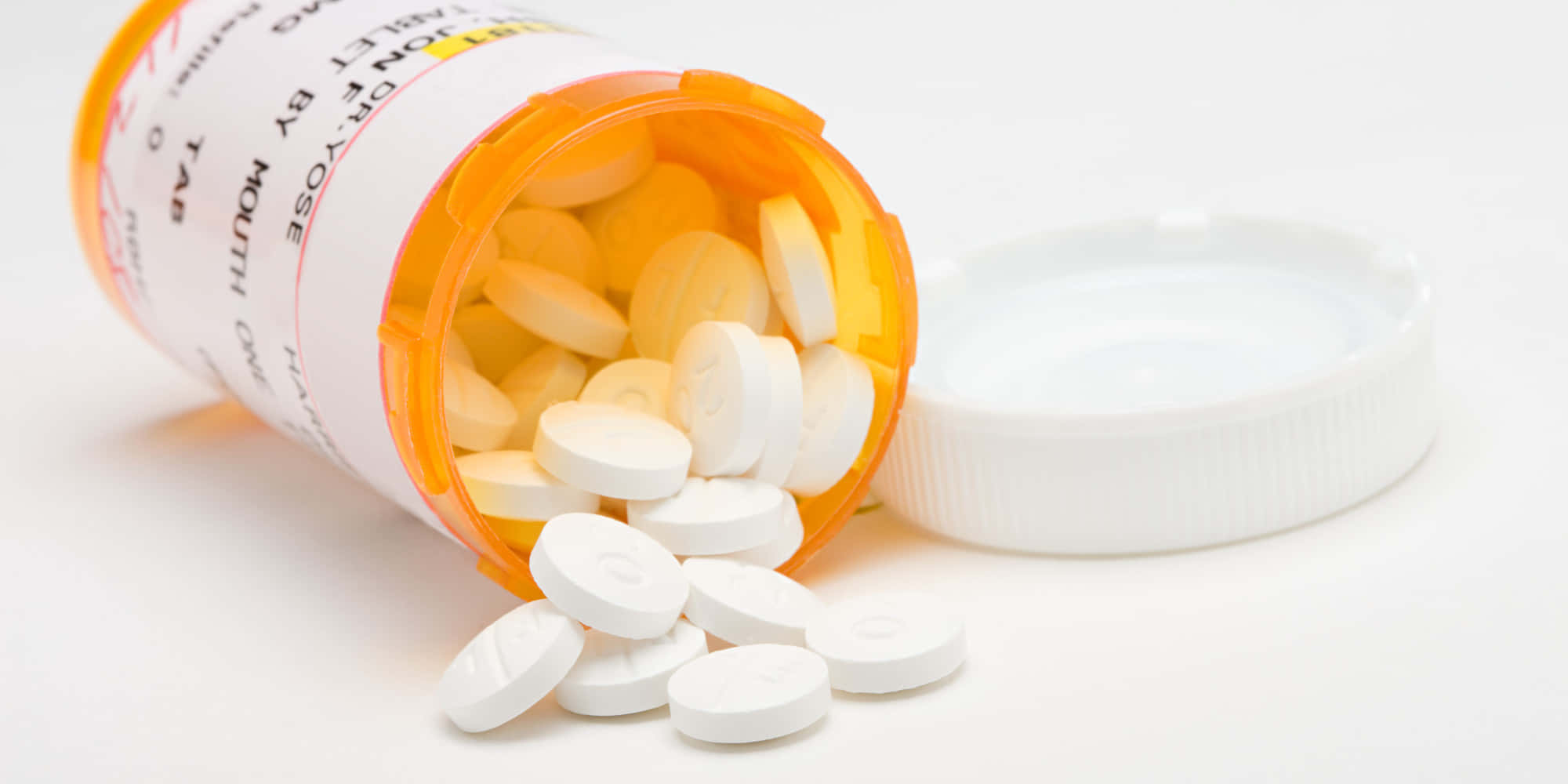 medicine 桌布 壁紙 — 一個橙色藥瓶翻倒，白色藥丸灑在純白表面上，瓶蓋在旁邊。