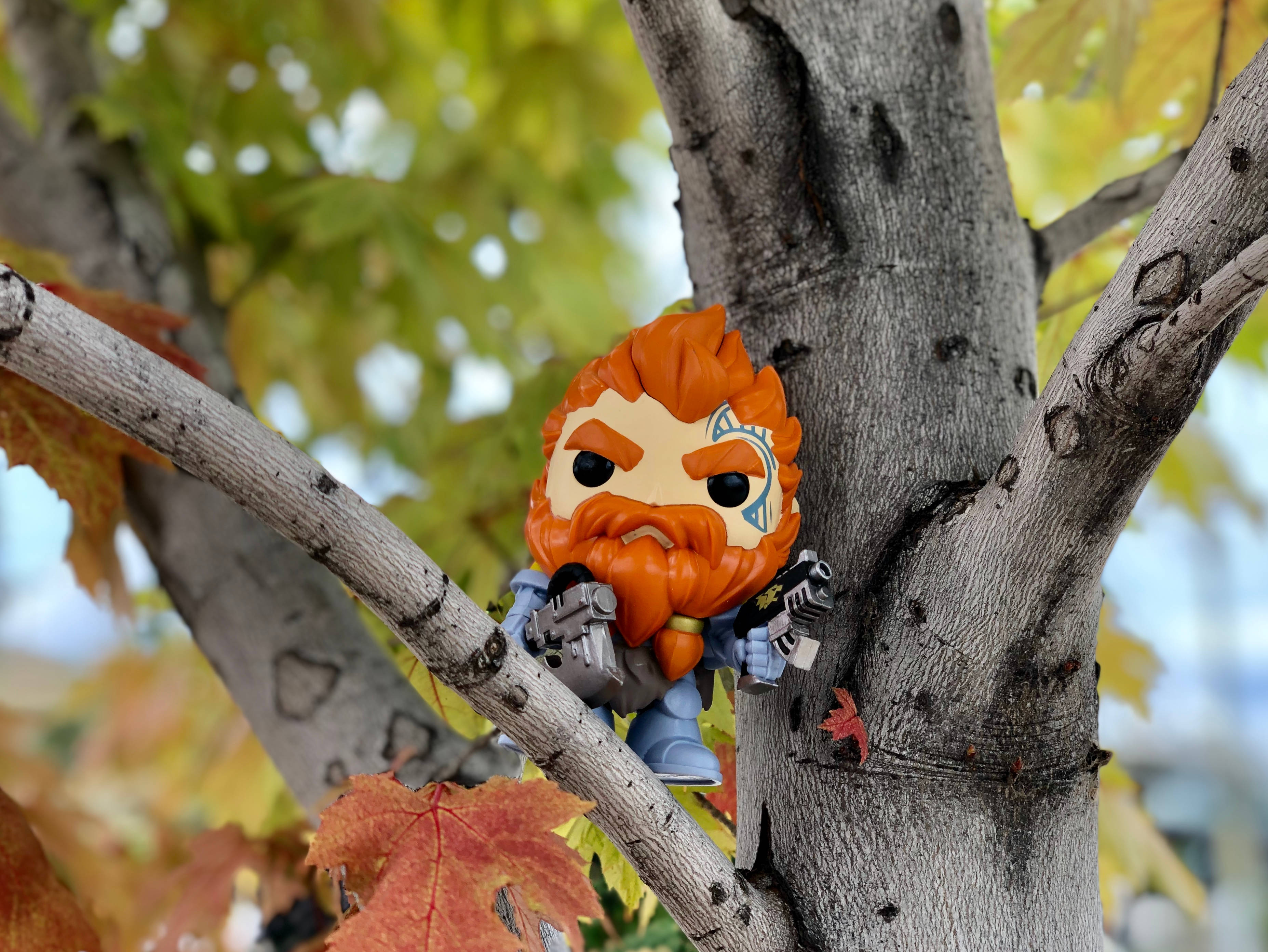 Funko Pop 桌布 壁紙 — 一個橙色頭髮和鬍子的Funko Pop!公仔抓緊樹枝，周圍是秋葉。
