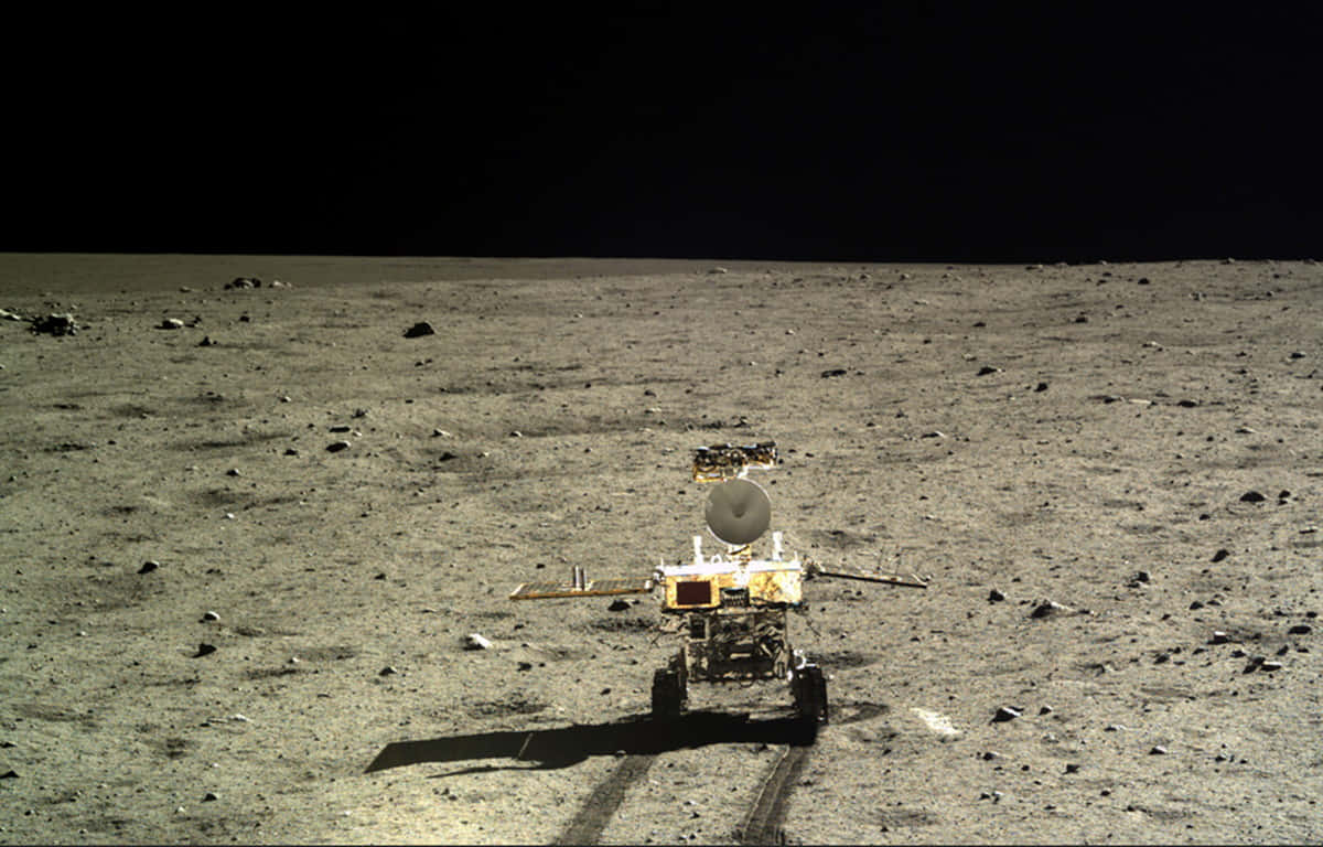 Lunar Rover 桌布 壁紙 — 一個機器人探測車站在荒蕪的灰色月球表面，在黑色天空下投下長長的影子。