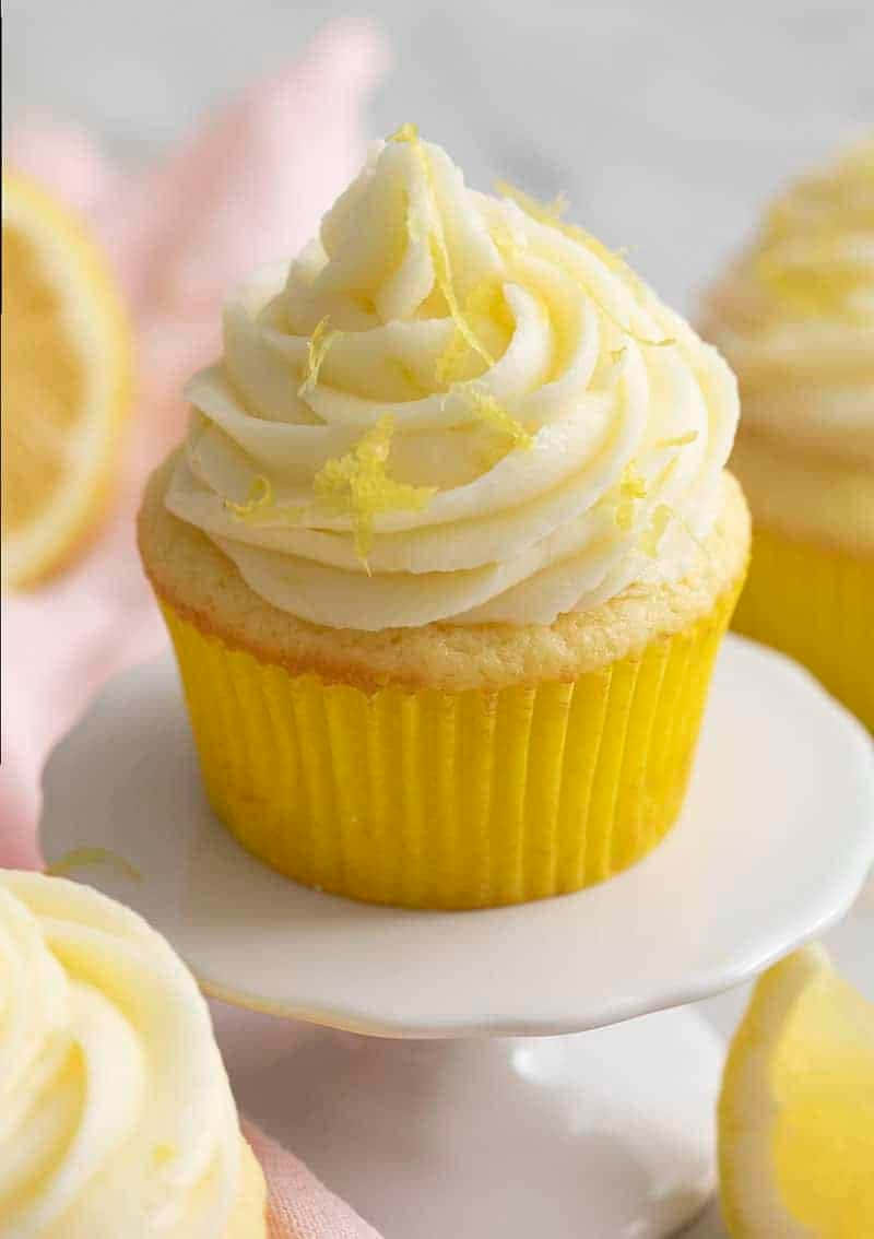 Cupcake 桌布 壁紙 — 一個檸檬杯子蛋糕的近距離特寫，帶有奶油糖霜和檸檬皮裝飾，放在白色支架上。