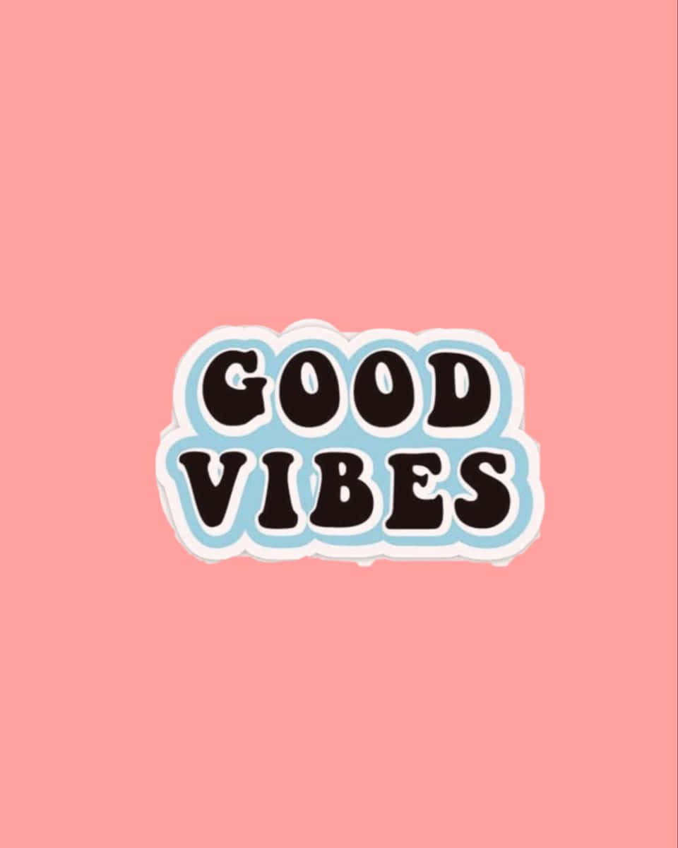 70年代動圖 桌布 壁紙 — 一個歡快的「GOOD VIBES」貼紙圖案，採用粗體黑色字體，帶有淺藍色和白色輪廓，背景為純粉色。