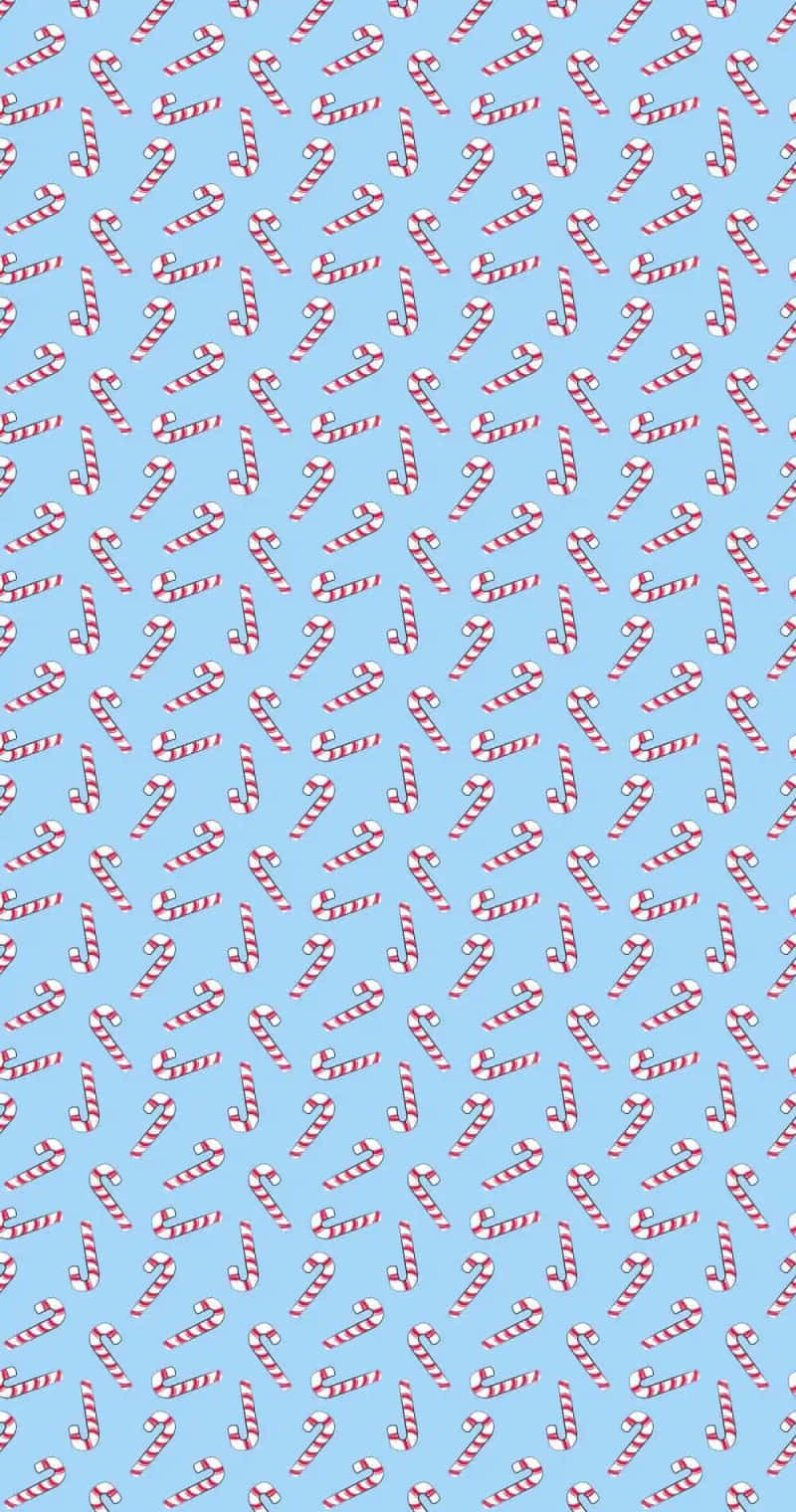 Cute Simple Christmas 桌布 壁紙 — 一個歡樂的圖案，紅白條紋的拐杖糖散落在柔和的藍色背景上。