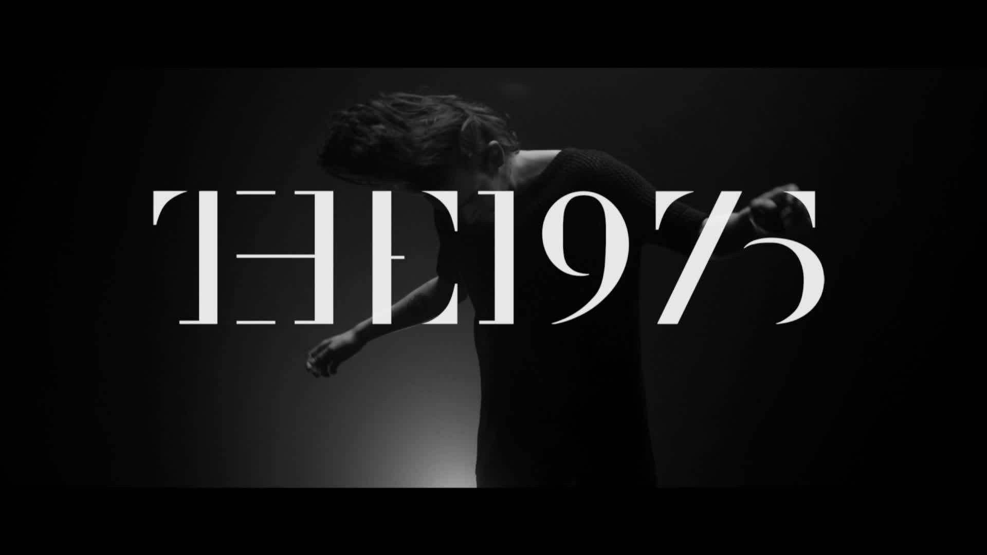 The 1975 桌布 壁紙 — 一個正在移動的人物單色剪影，在深色漸變背景上帶有粗體白色文字 'THE 1975'。