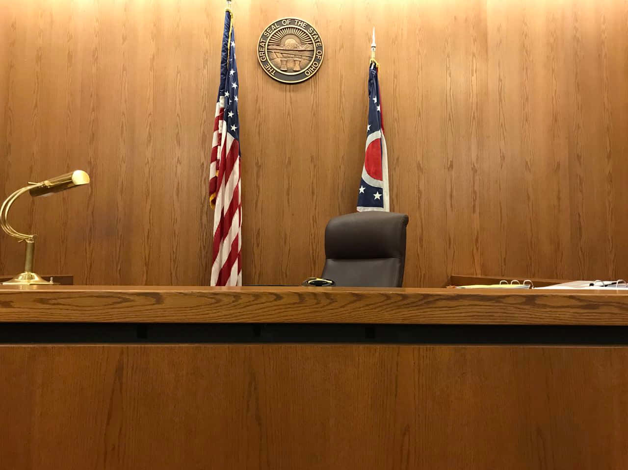 Court 桌布 壁紙 — 一個正式的法庭桌子，配有木質鑲板、美國和俄亥俄州旗幟，以及皮革椅子上方的州徽。