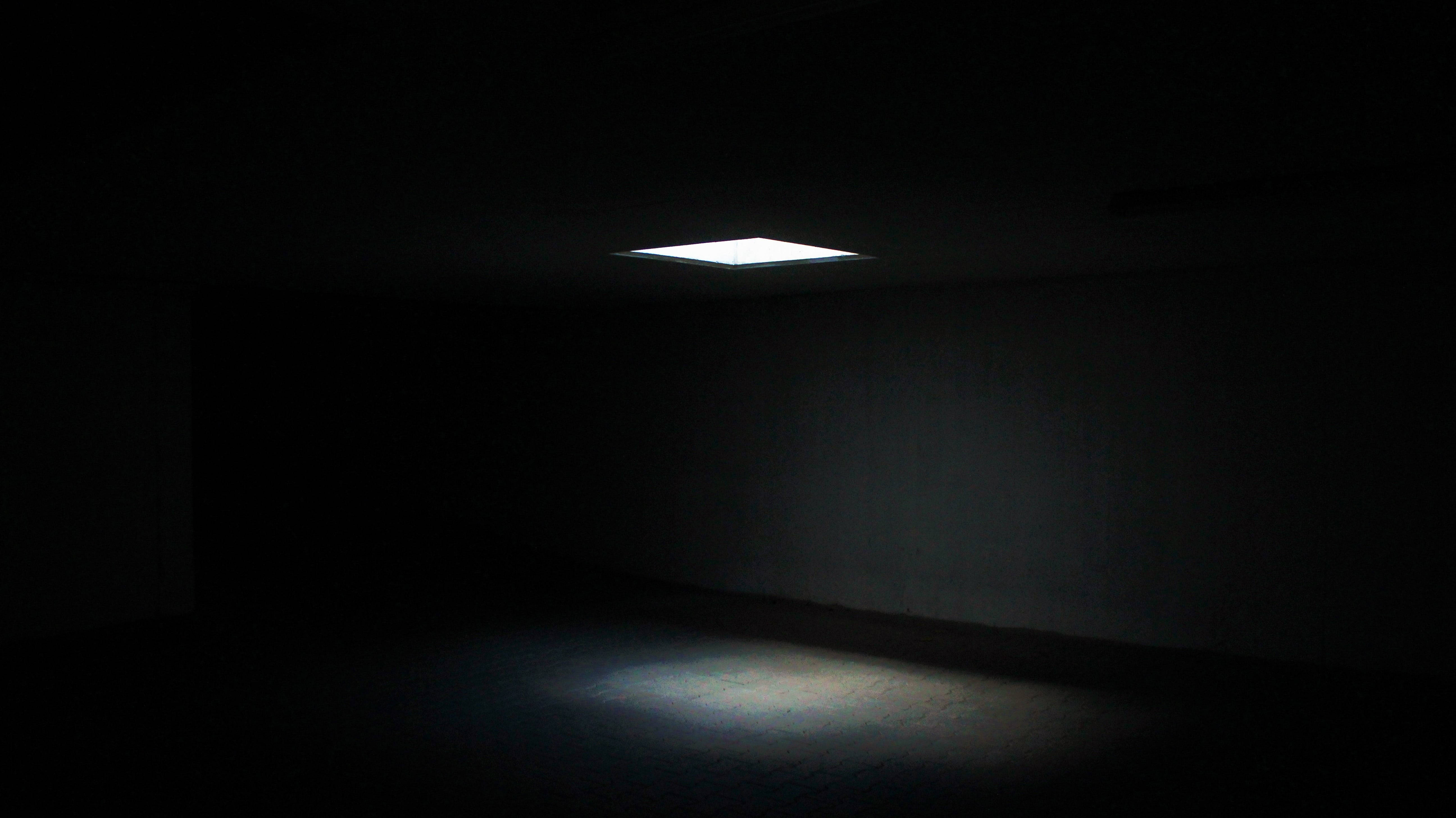 Dark 4K 桌布 壁紙 — 一個正方形的天花板燈在一個空的黑暗房間的地板上投射出強烈的光芒。
